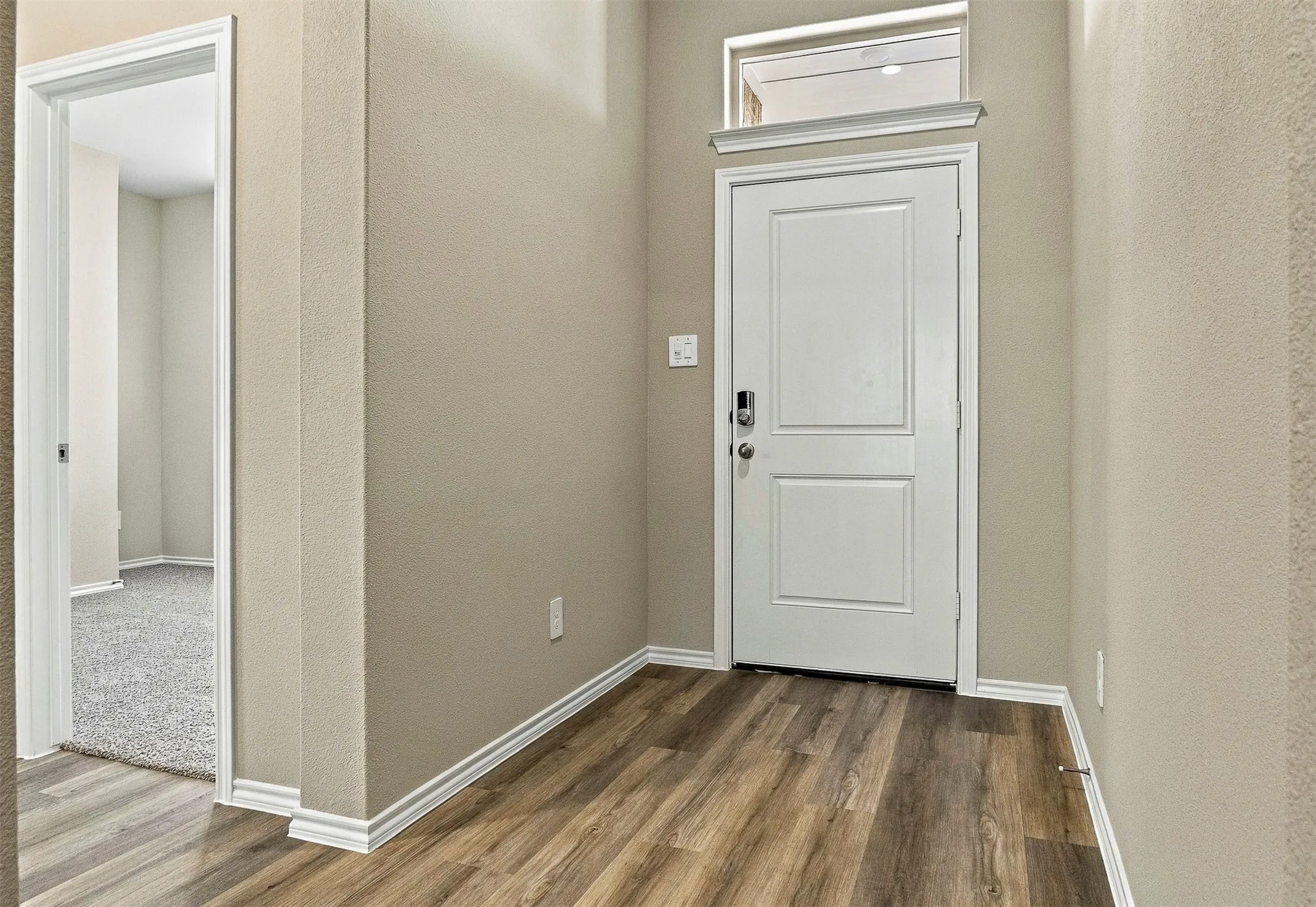 Entryway featuring wood-finish flooring and a white paneled door.