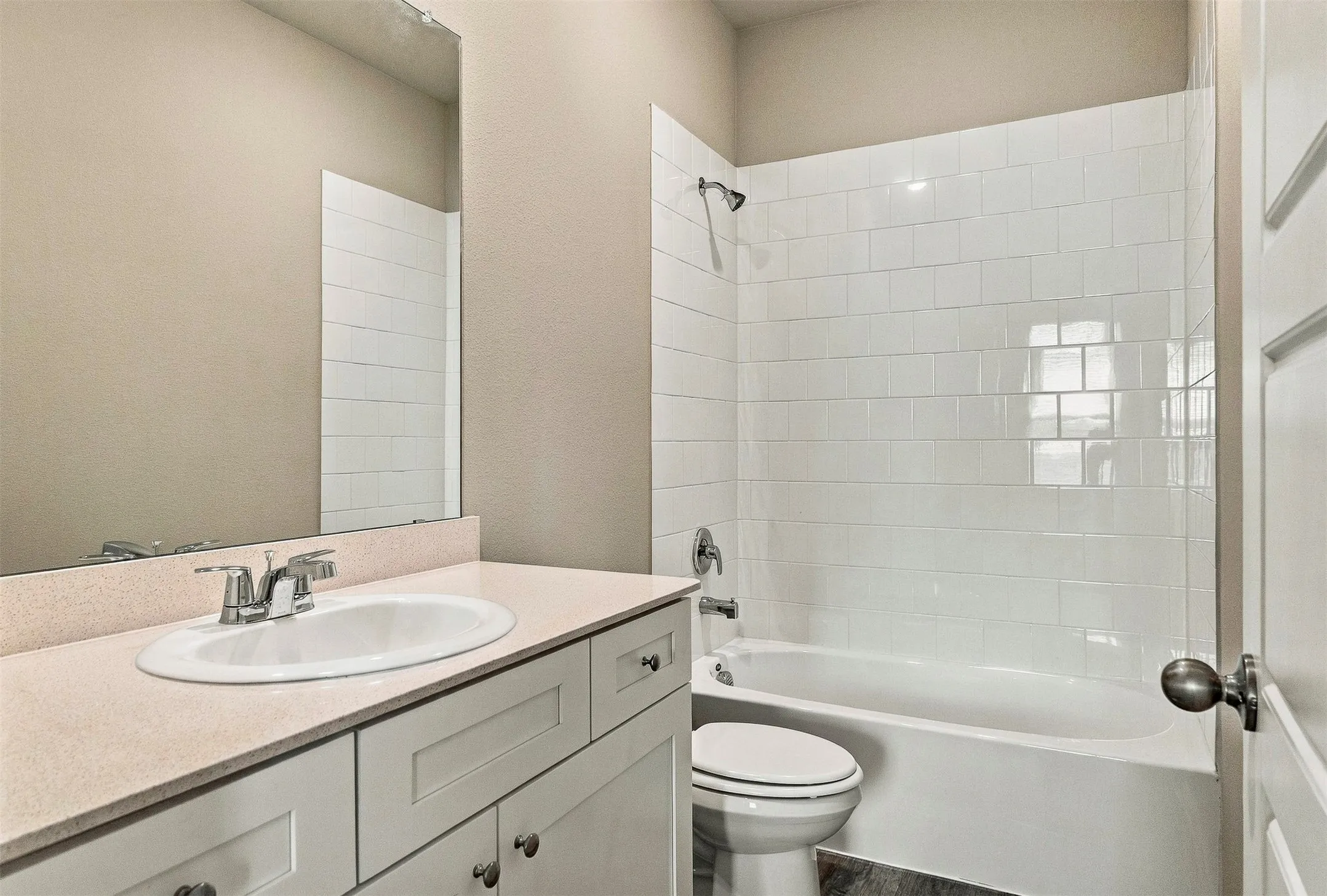 Built-in vanity with light-colored countertop, undermount sink, and chrome faucet