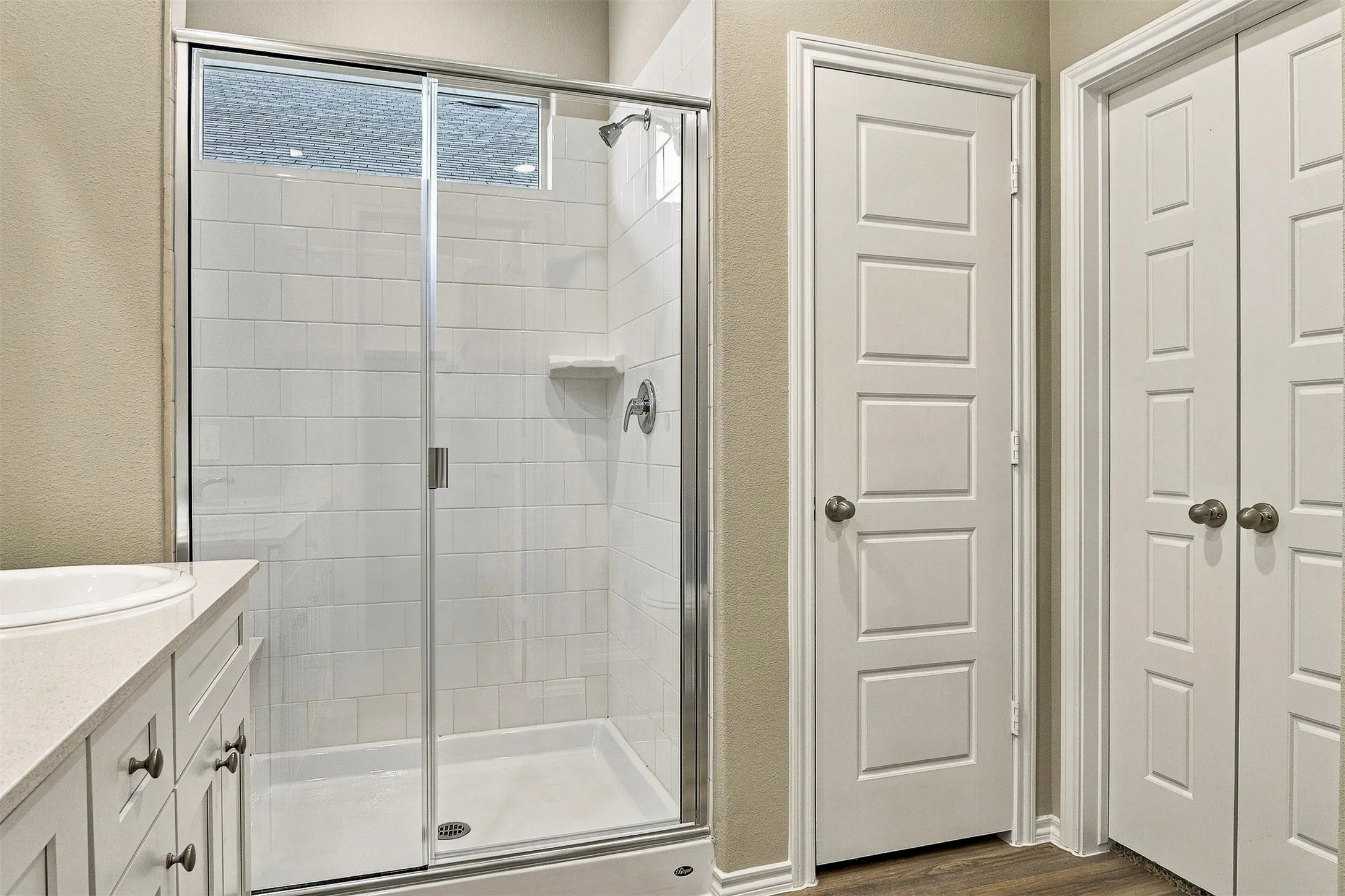 Shower enclosure with clear glass door, white subway tile surround, and built-in shelving