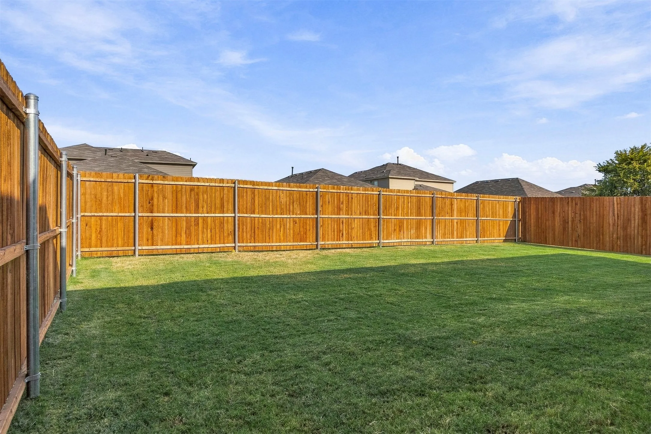 Expansive yard featuring a manicured lawn and privacy fencing
