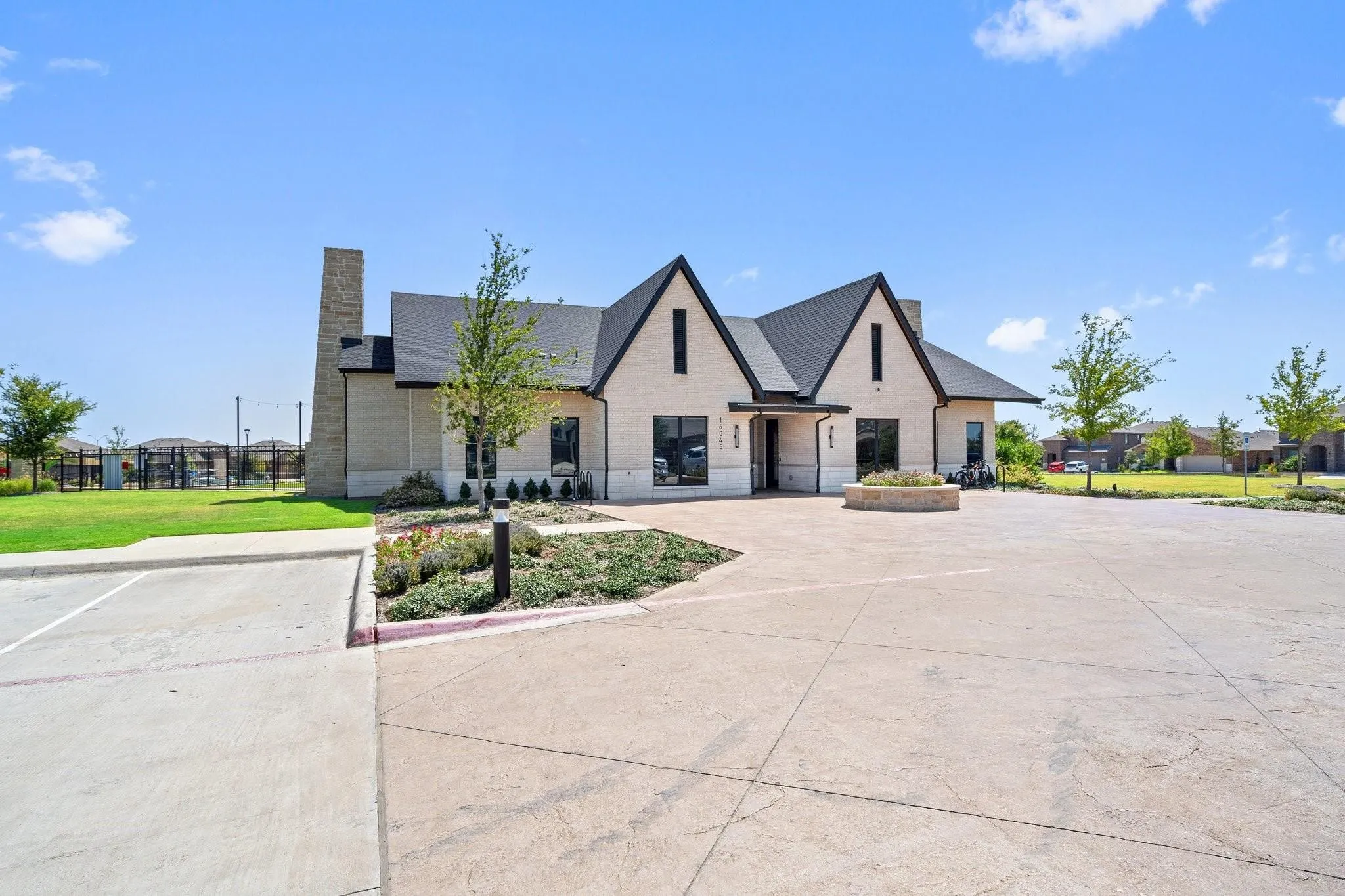 Contemporary community building exterior featuring a light-colored stucco finish, dark-trimmed gables, and a prominent stone chimney