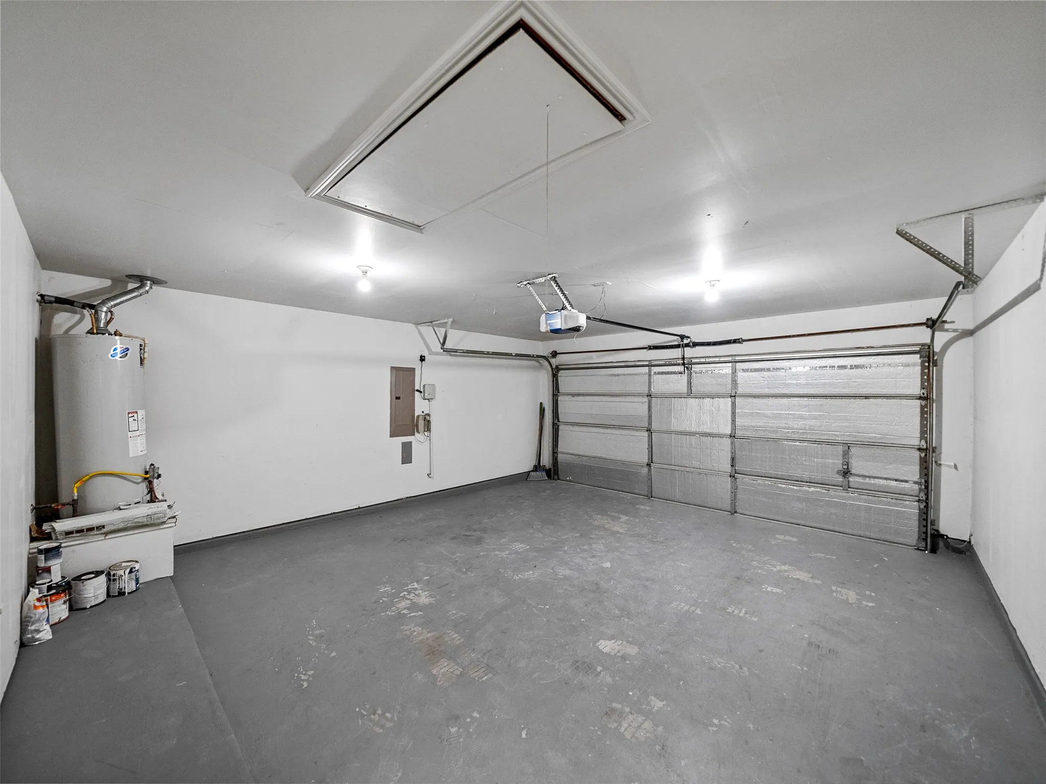 Attached garage with painted concrete flooring, an automatic garage door opener, and a water heater
