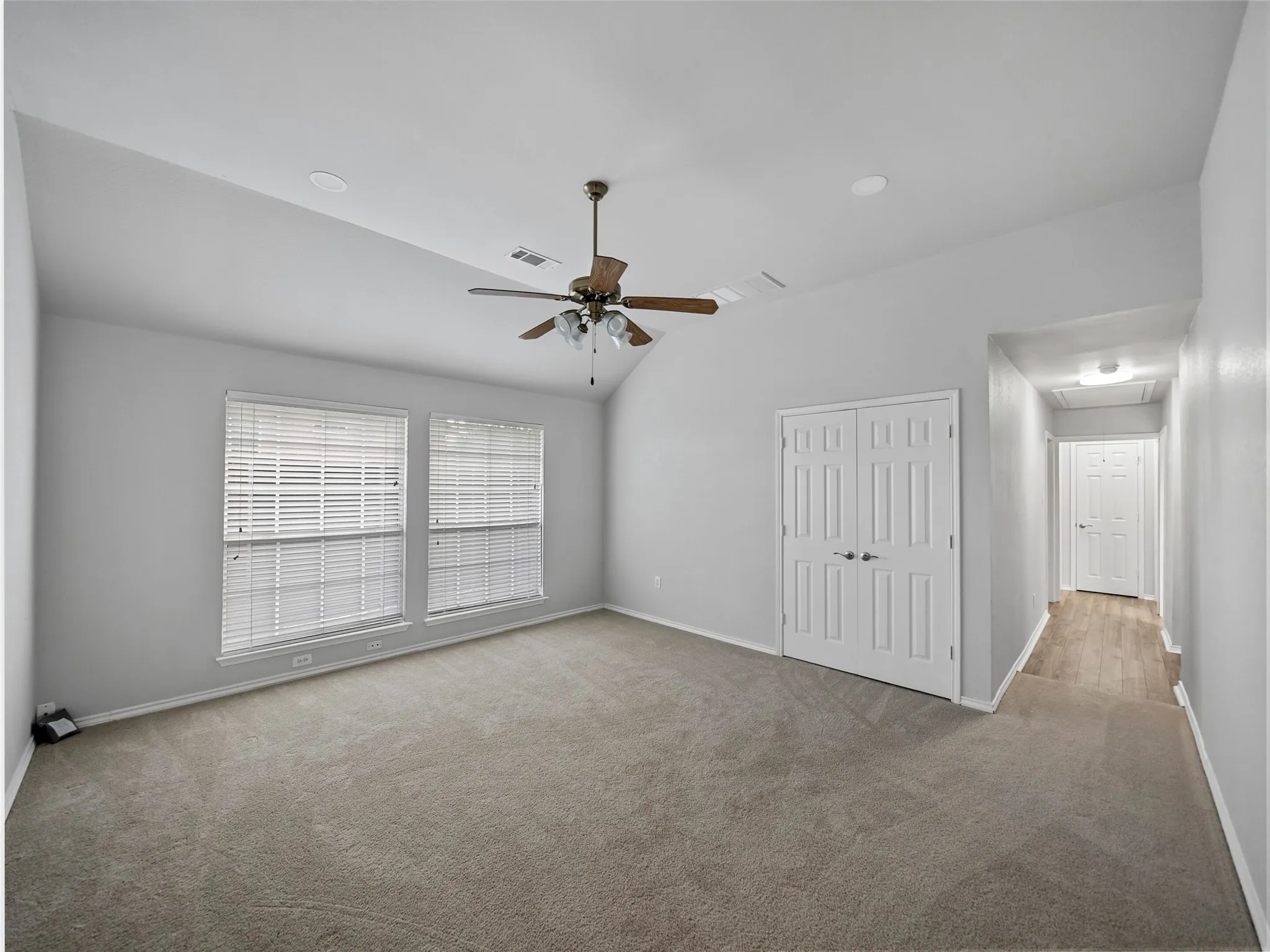 Vaulted ceiling with a ceiling fan, dual windows with blinds, recessed lighting, and carpet flooring