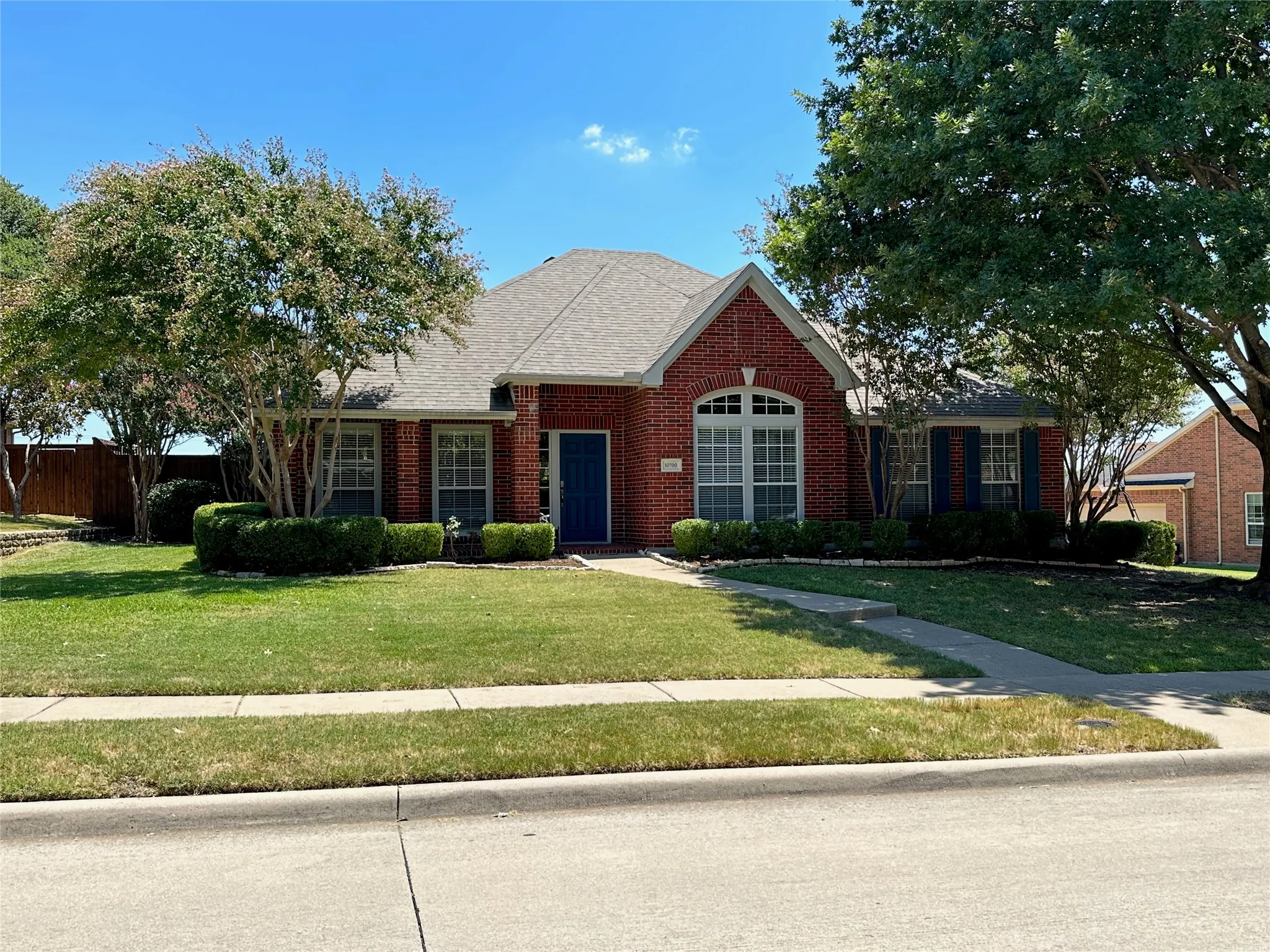 Brick exterior with a gabled roofline, arched window, and landscaped front yard