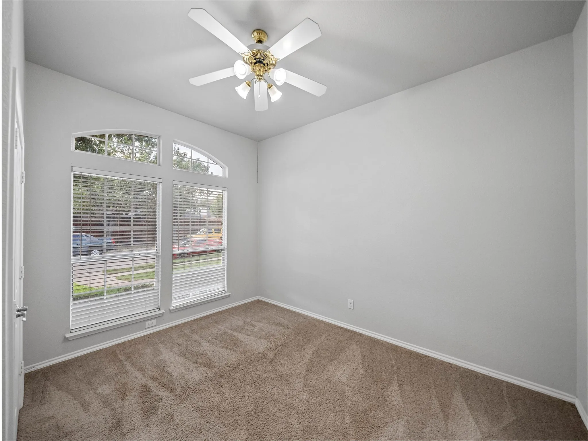 Vaulted ceiling with a ceiling fan, arched transom windows, two large windows with blinds, and neutral carpet flooring