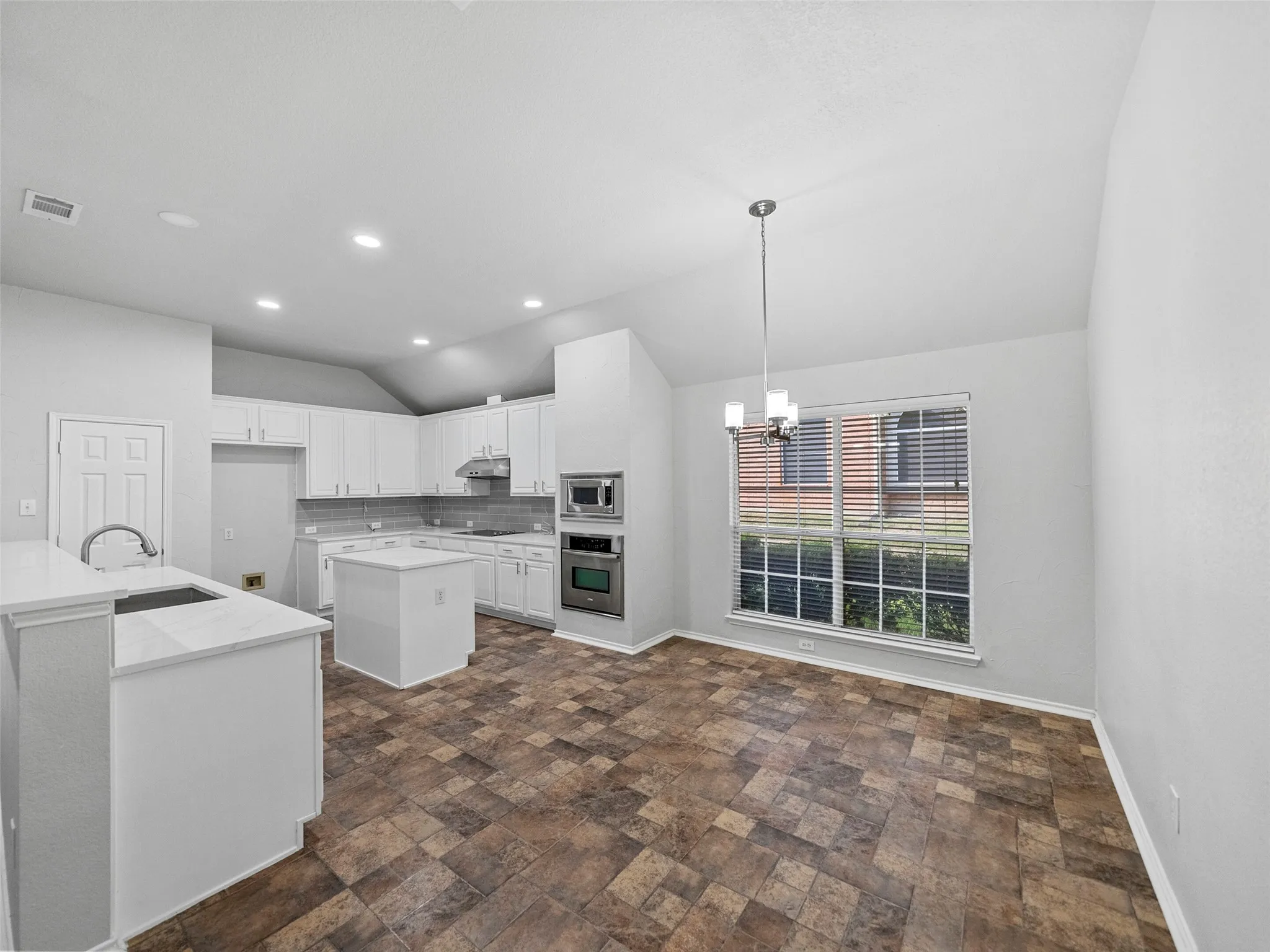 Kitchen and dining area featuring white cabinetry, stainless steel appliances, a center island, and wood-finish flooring