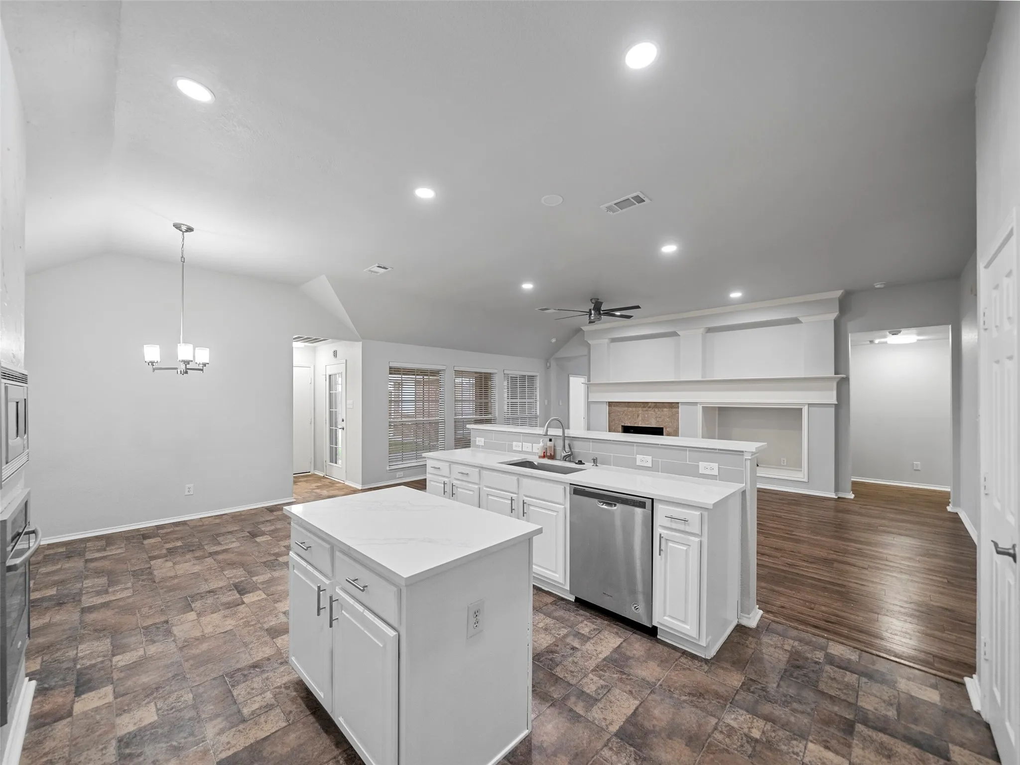 Kitchen and living area featuring a central island, built-in stainless steel appliances, a fireplace with a mantel, and recessed lighting