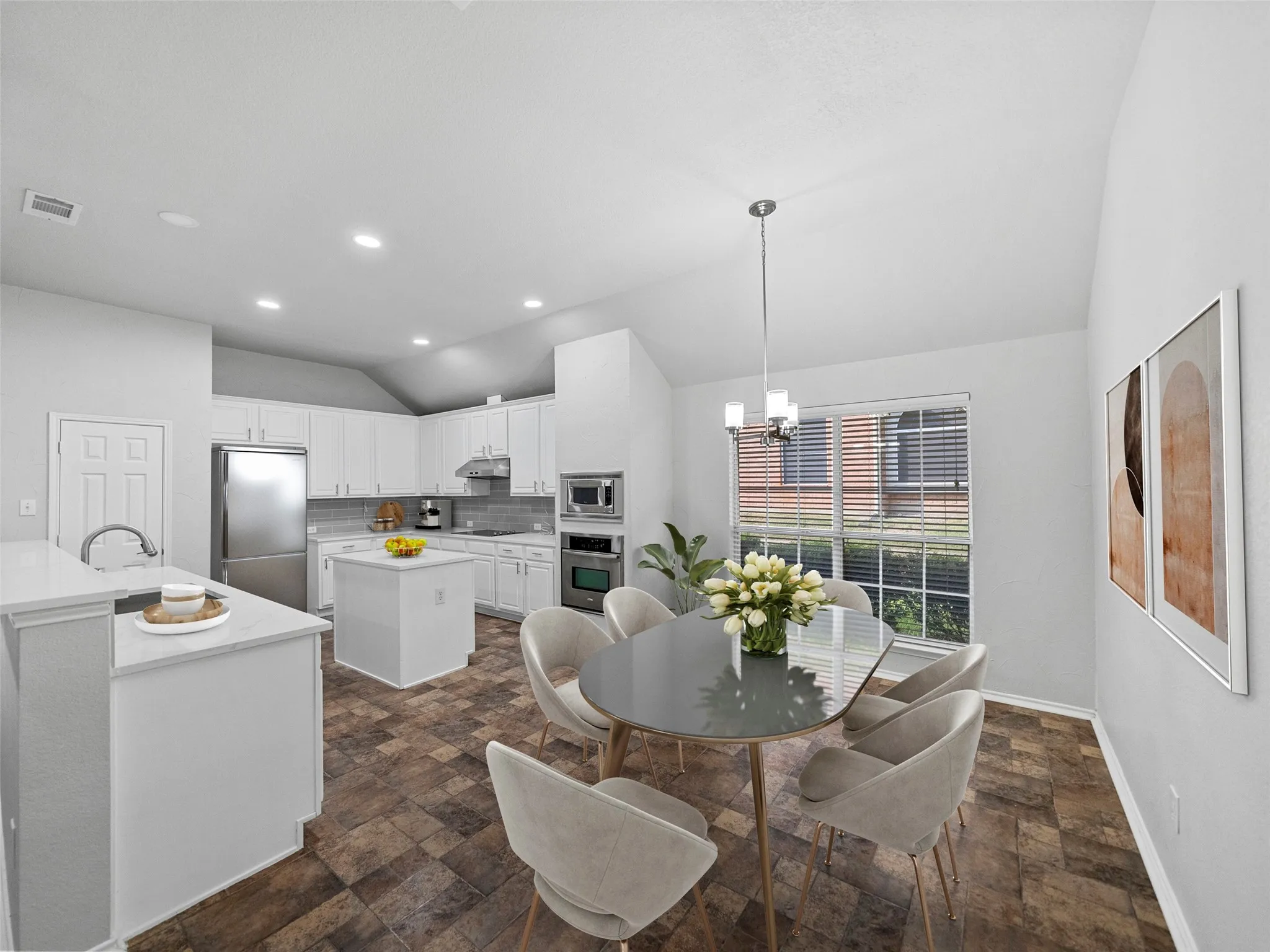 Kitchen and dining area featuring vaulted ceilings, white cabinetry, a kitchen island, stainless steel appliances, and a pendant light fixture