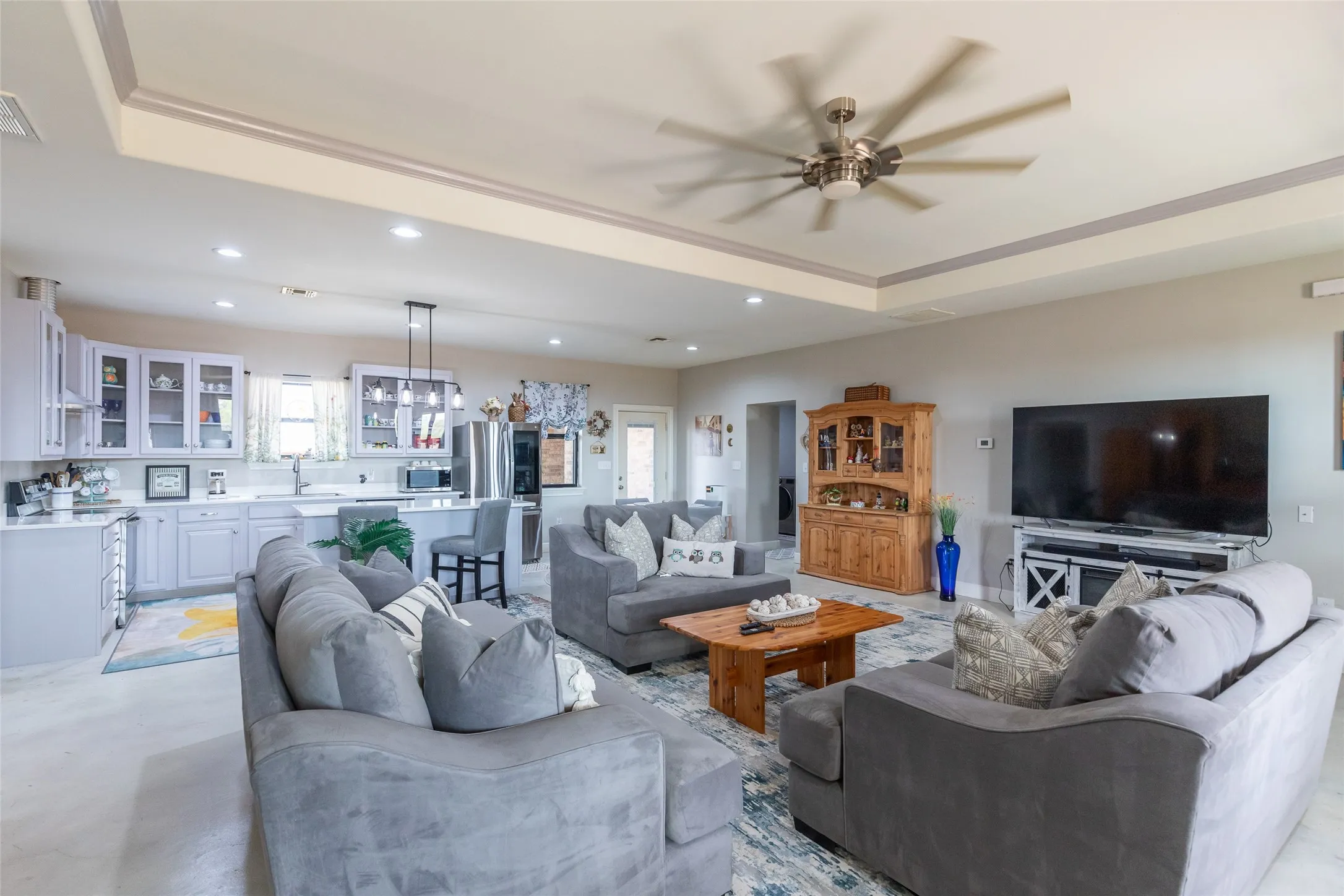 Open-concept living space with a tray ceiling and ceiling fan