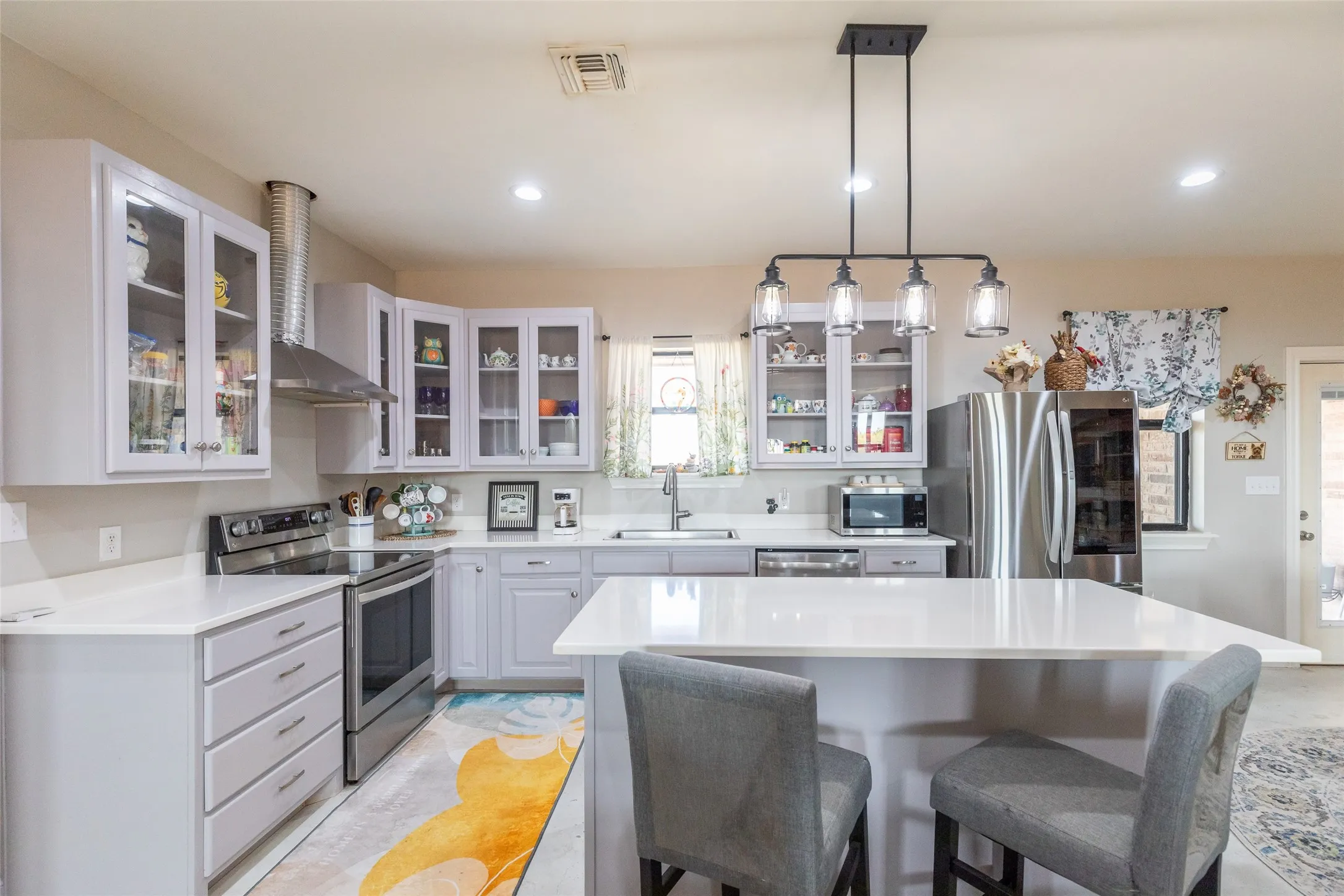White shaker cabinetry, stainless steel appliances, white countertops, built-in island, and recessed lighting
