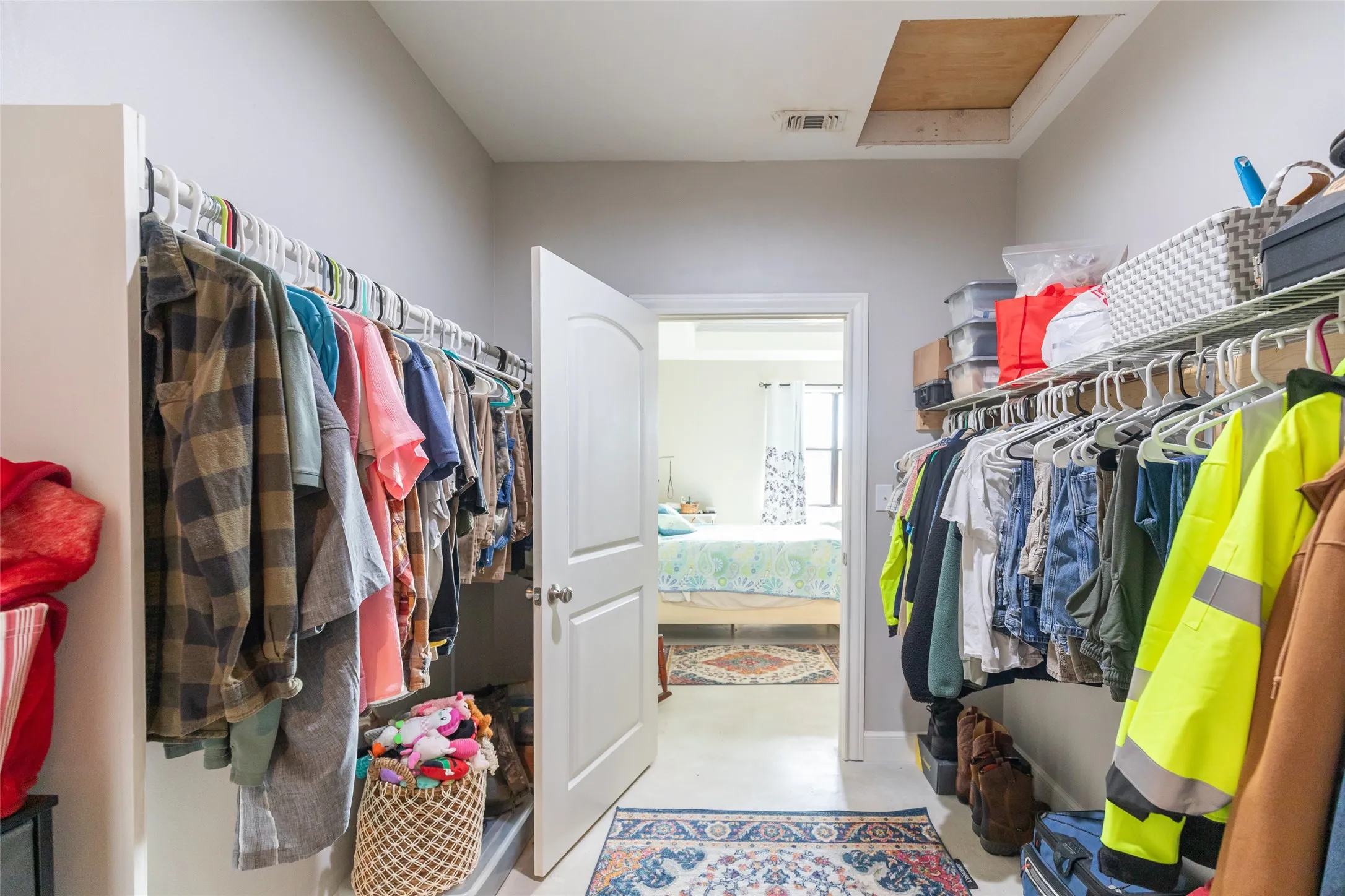Walk-in closet featuring built-in shelving, hanging rods, and a white interior door with a rounded arch panel