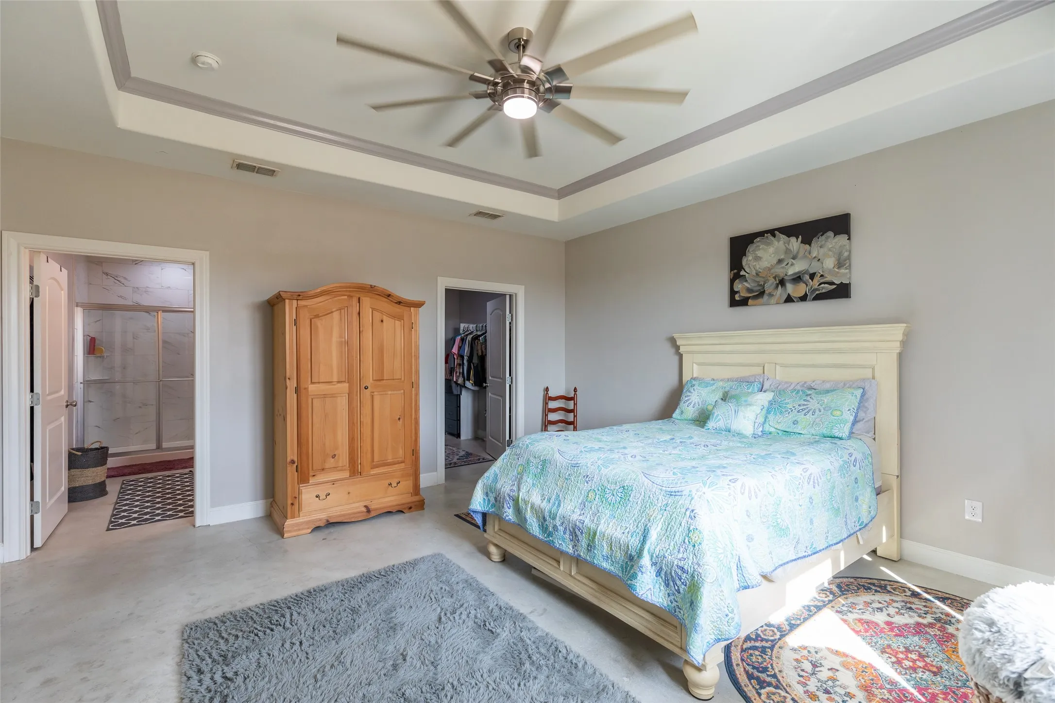 Tray ceiling with recessed lighting and a ceiling fan, light gray wall paint, light-toned flooring, and an adjoining walk-in closet