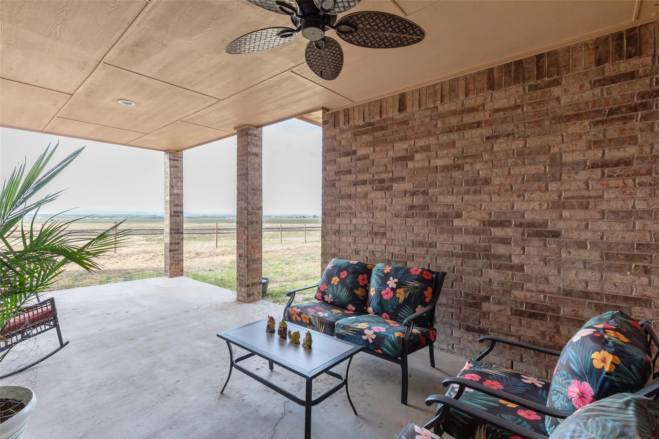 Covered patio featuring a ceiling fan, recessed lighting, concrete flooring, and brick support columns