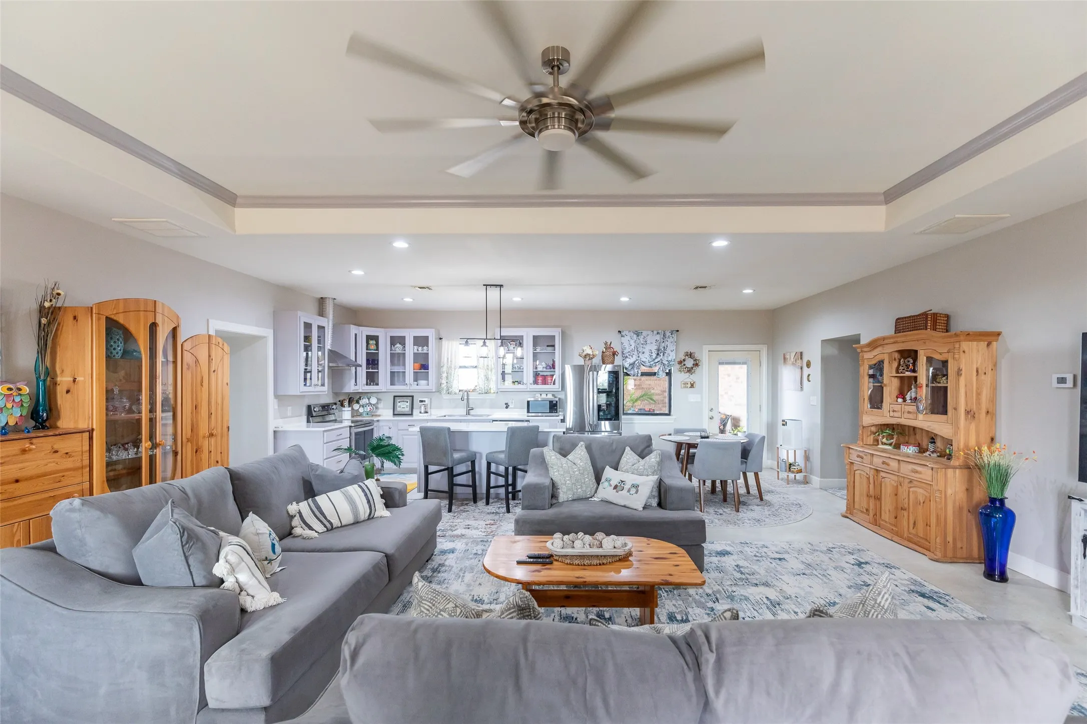 Open concept living area featuring a ceiling fan, recessed lighting, and a tray ceiling
