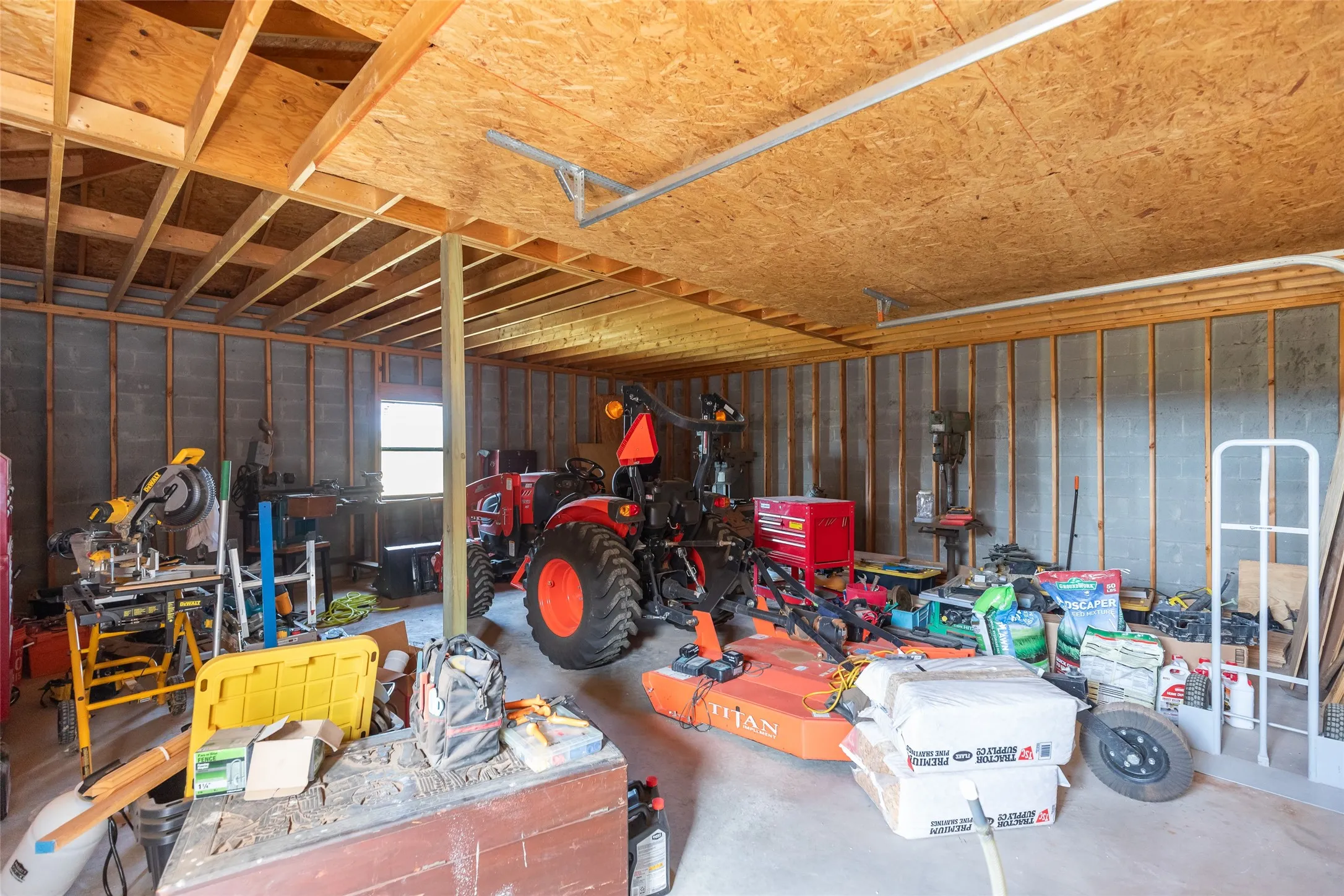 Utility room with exposed ceiling joists, concrete block walls, and a single window
