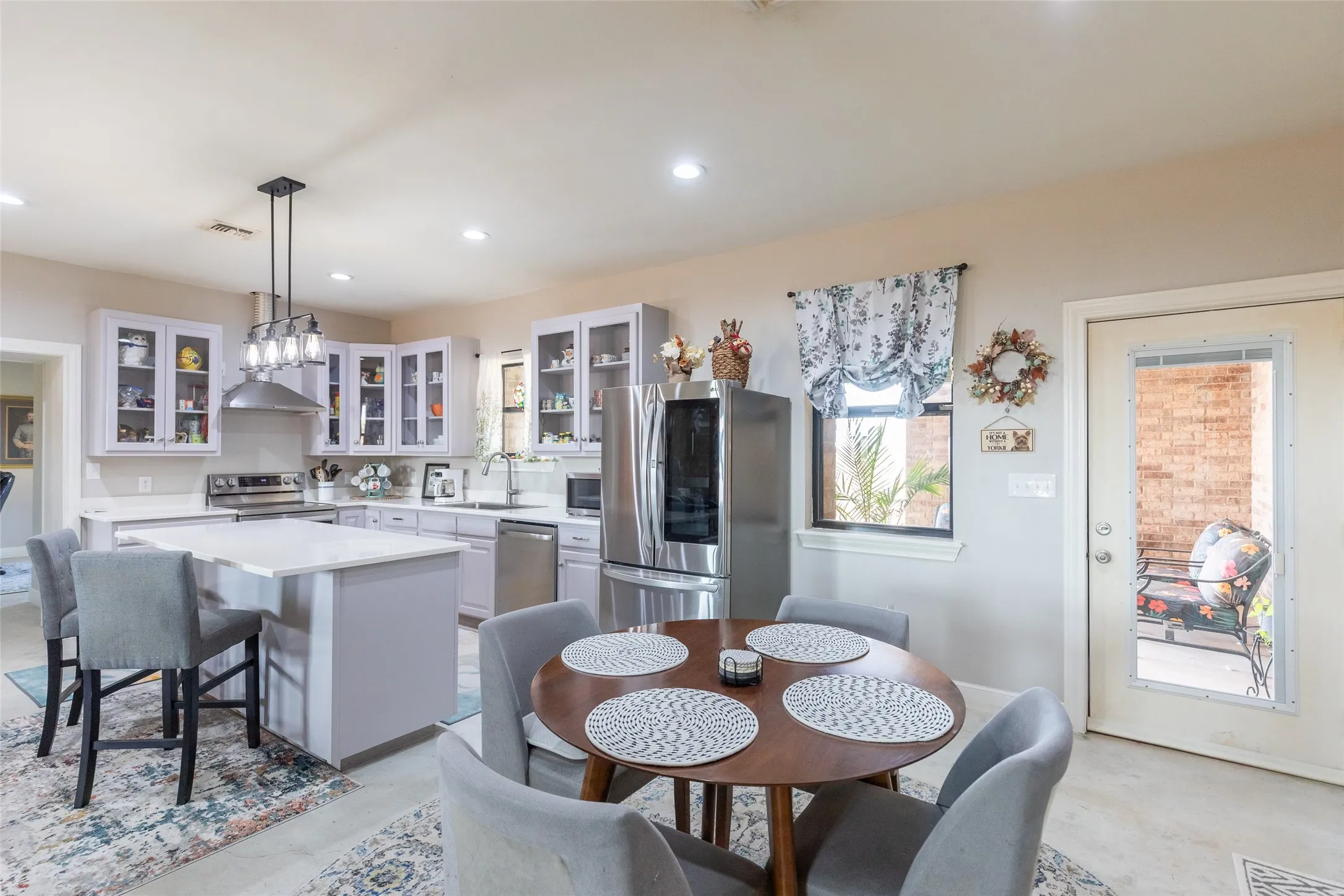 Kitchen featuring a central island with seating, pendant lighting, stainless steel appliances, and light-toned cabinetry
