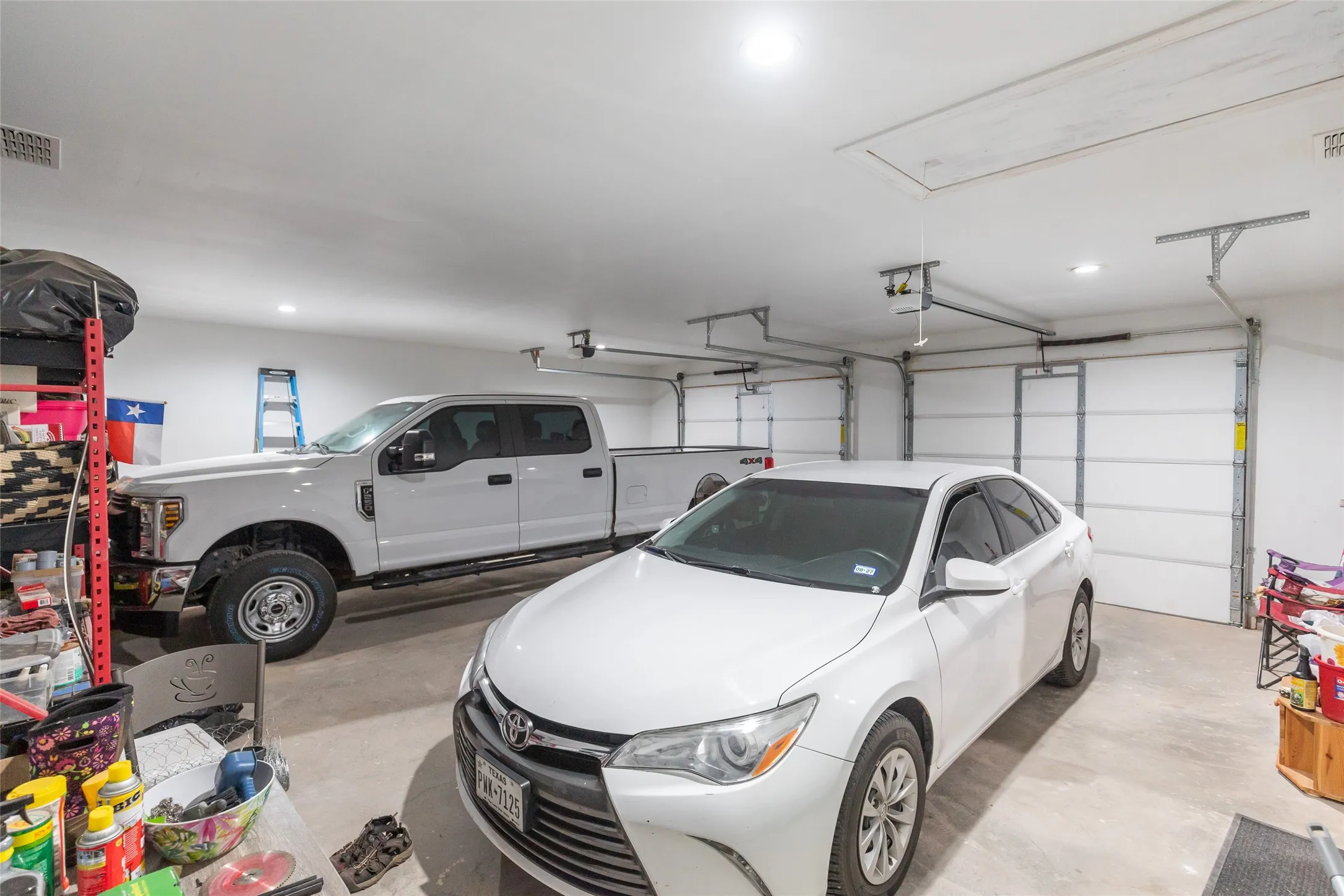 Spacious garage featuring two overhead doors, recessed lighting, and a finished ceiling