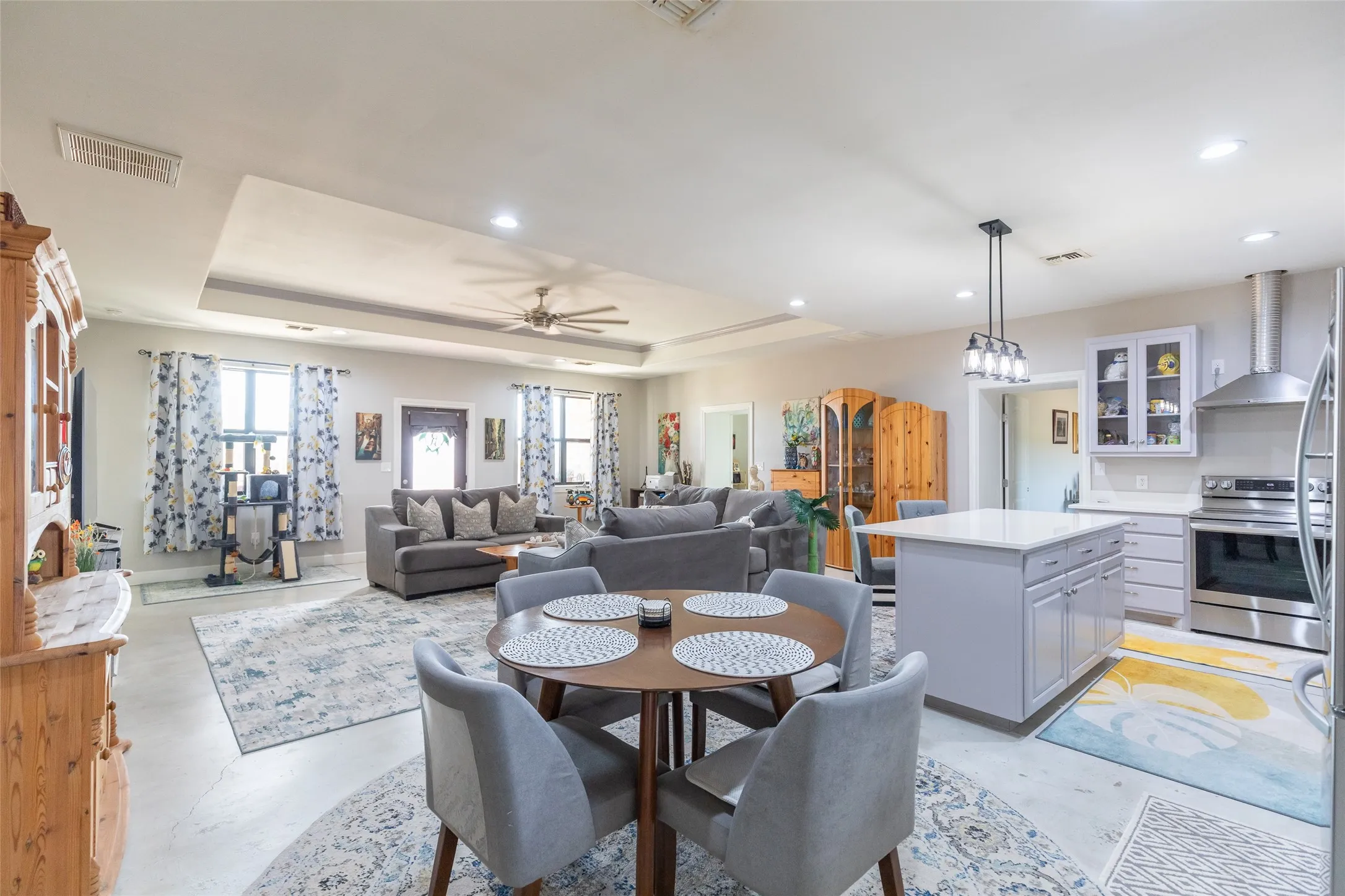 Tray ceiling with recessed lighting, stainless steel appliances, kitchen island with built-in storage, pendant lighting, and a ceiling fan