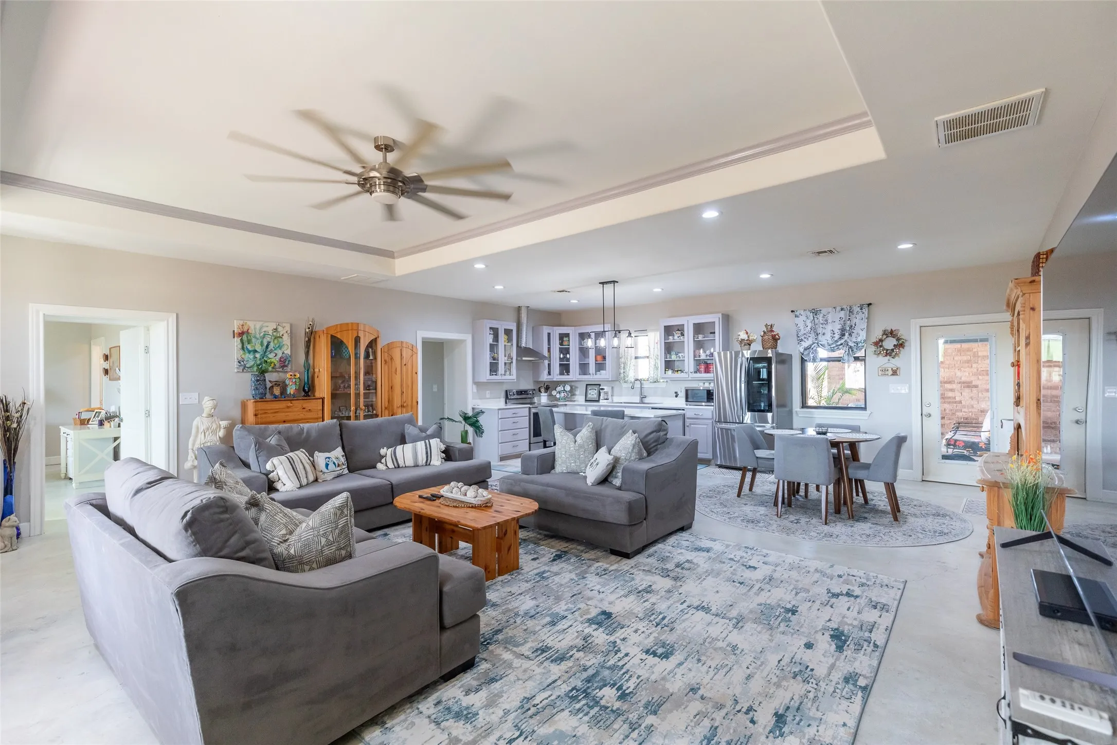 Open-concept living space with tray ceiling, recessed lighting, and a modern ceiling fan