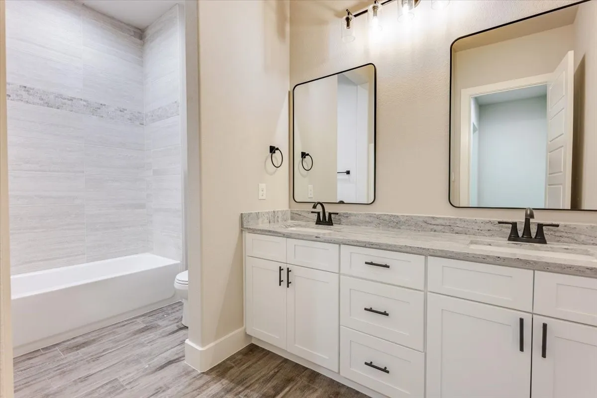 Dual vanity with granite countertops, white cabinetry, and matte black fixtures