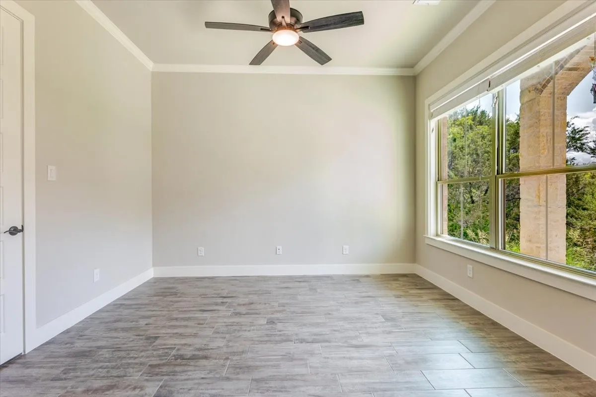 Wood-finish flooring, crown molding, and a ceiling fan with integrated lighting
