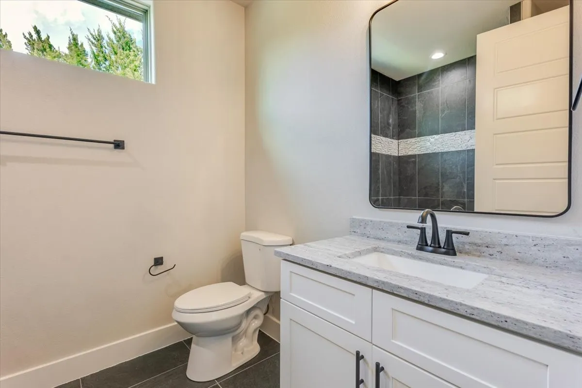 White vanity with flat panel doors, light-toned countertop, rectangular undermount sink, and dark-finished faucet
