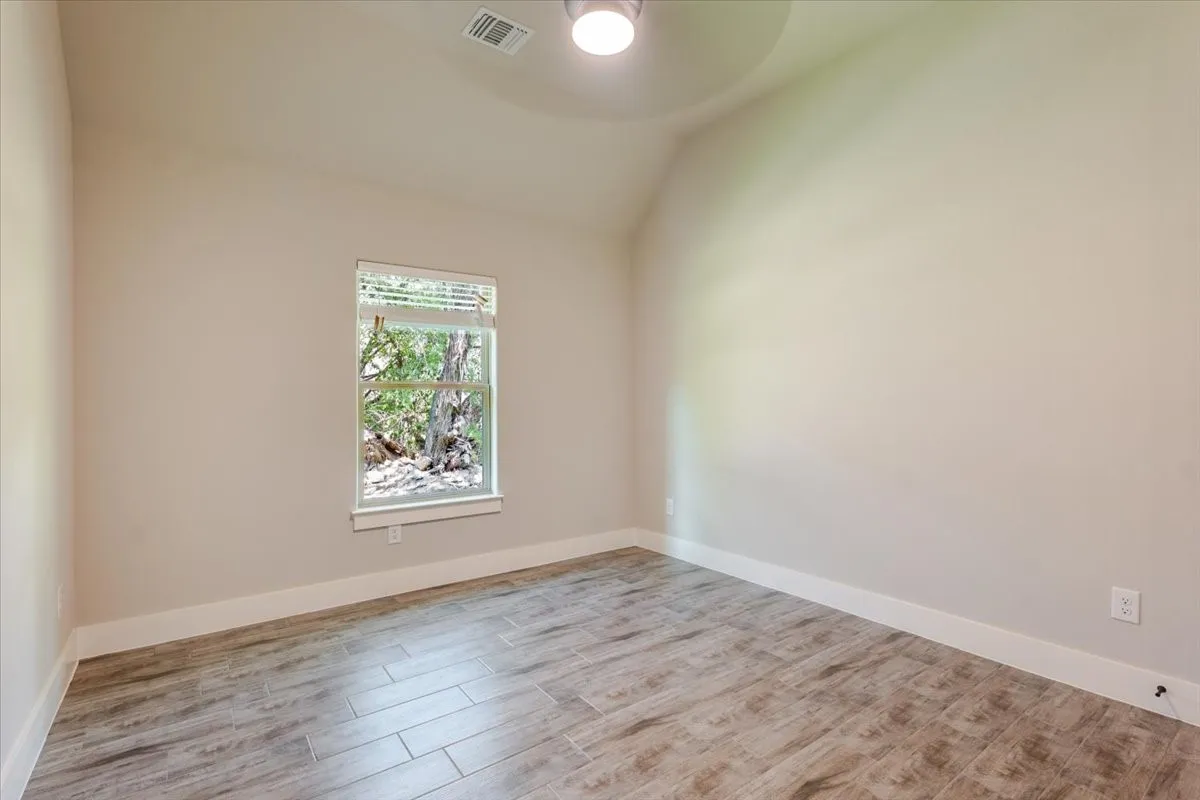 Room featuring wood-finish tile flooring, neutral wall paint, and a single window with blinds