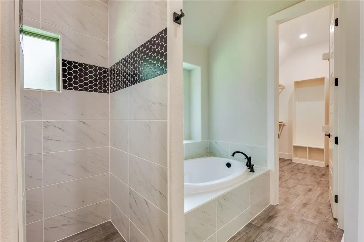 Walk-in shower with tiled walls and a hex tile accent band