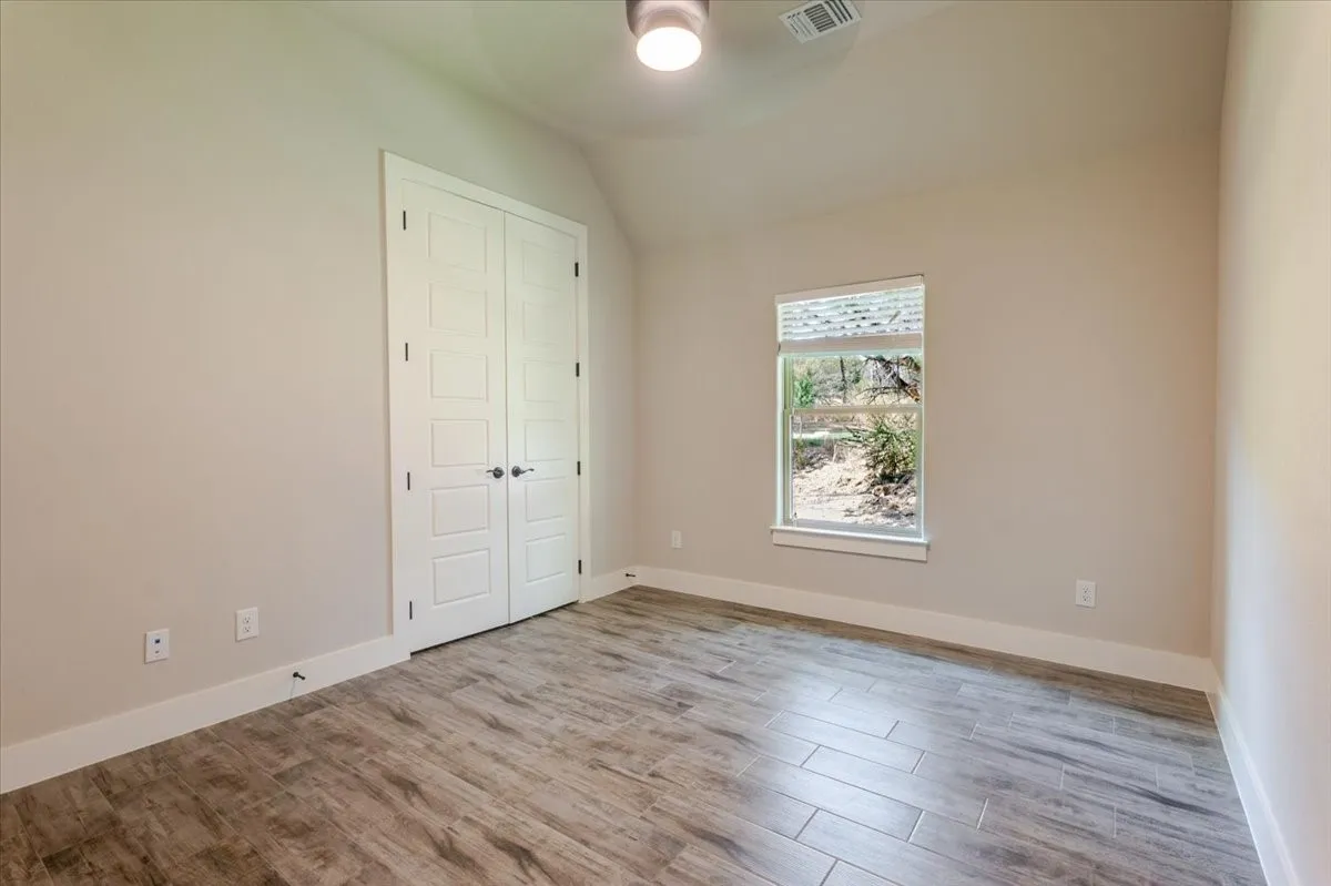 Wood-finish tile flooring, vaulted ceiling, and a built-in closet with panel doors