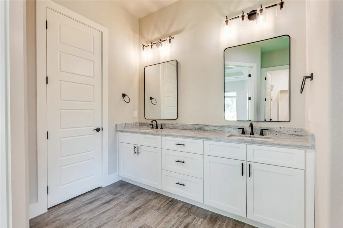 Dual vanity with white cabinetry, light stone-finish countertop, and matte black fixtures