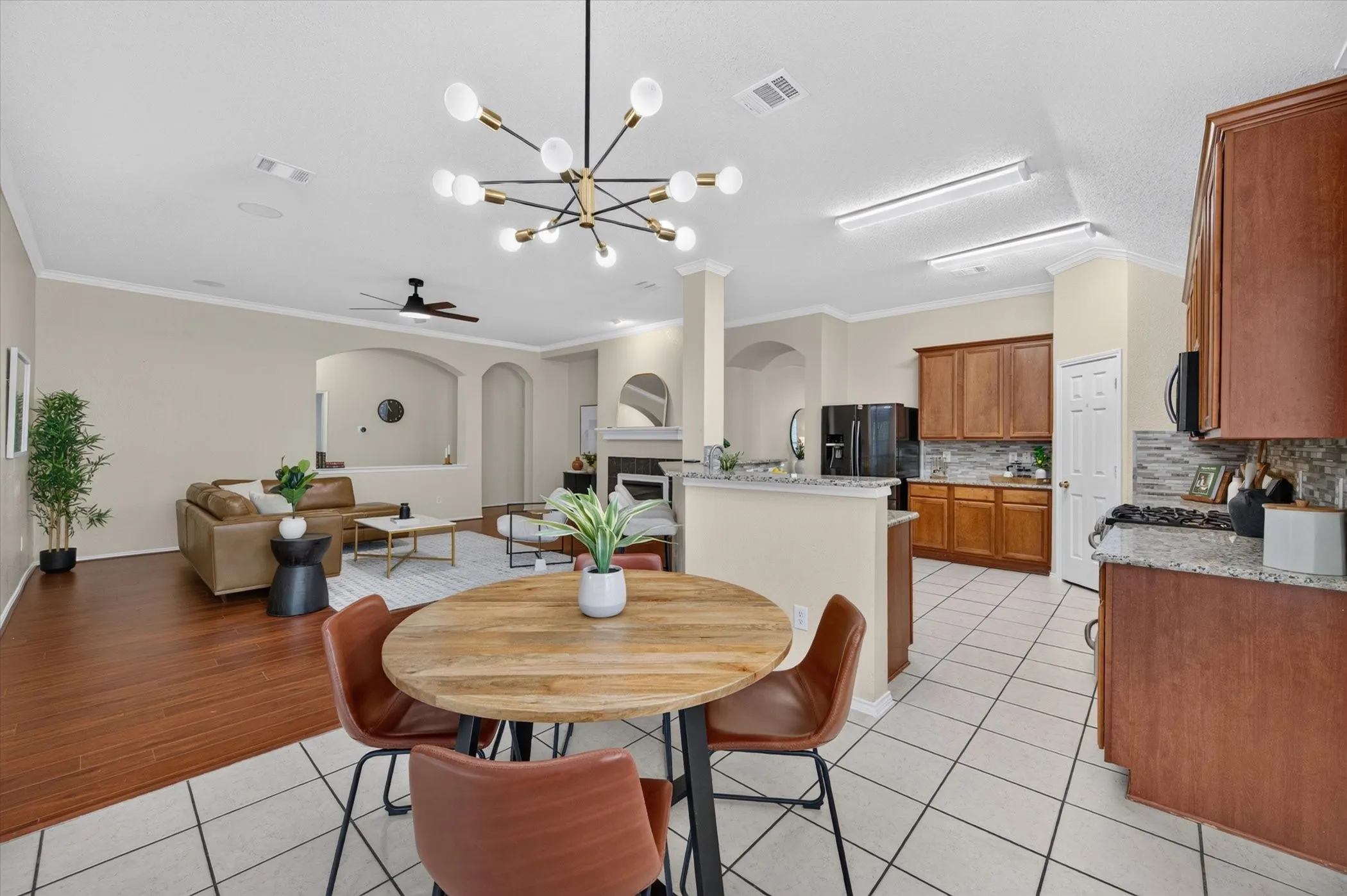 Open-concept area featuring a multi-light modern chandelier, wood-finish flooring, tile flooring, stone-finish countertops, and wood cabinetry