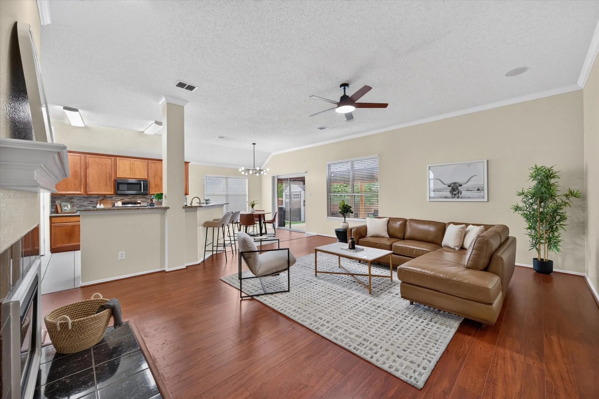 Open-concept interior featuring wood-finish flooring, vaulted ceilings, a fireplace with a black tile hearth, and sliding glass patio doors