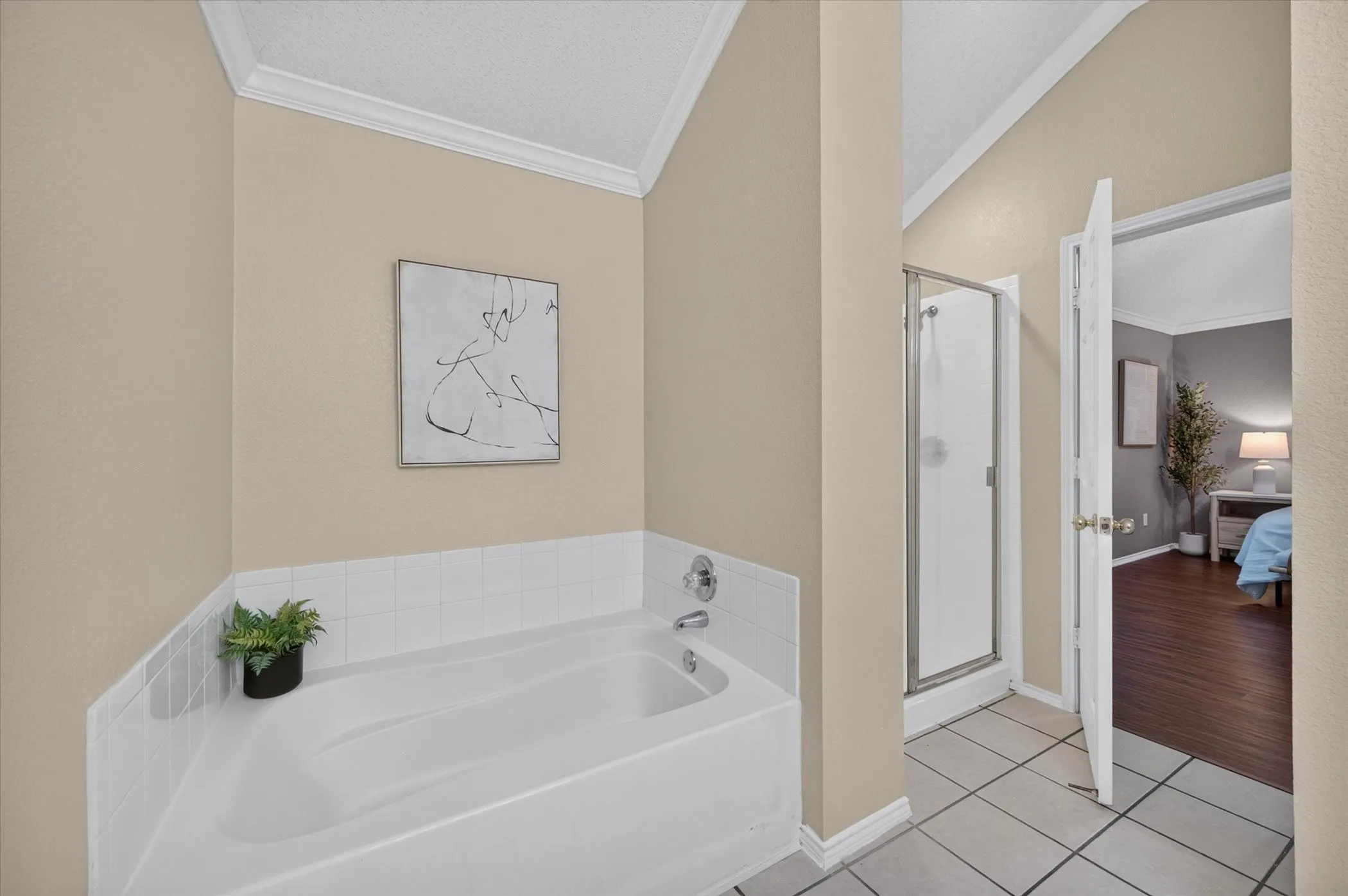 Bathroom featuring a vaulted ceiling, a built-in soaking tub with tile surround, and a walk-in shower with a framed glass door