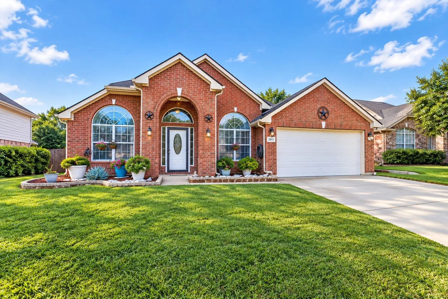 Traditional brick exterior featuring an arched entryway, gabled roofline, decorative star accents, and large arched windows