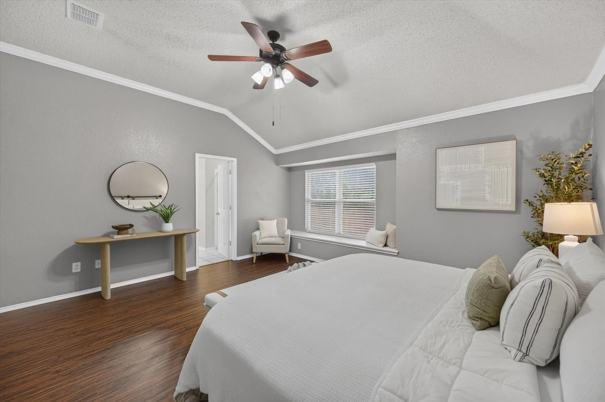 Vaulted ceiling with crown molding, wood-finish flooring, and a built-in window seat