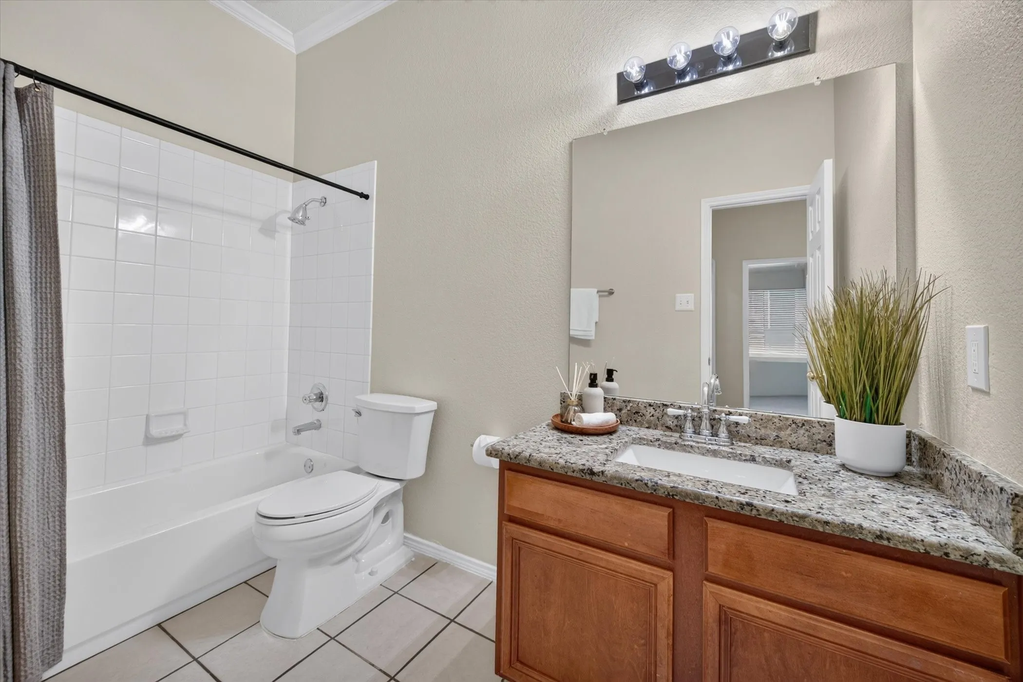 Bathroom featuring a wood vanity with a stone countertop, an integrated rectangular sink, a large wall-mounted mirror, and a tub-shower combination with tile surround