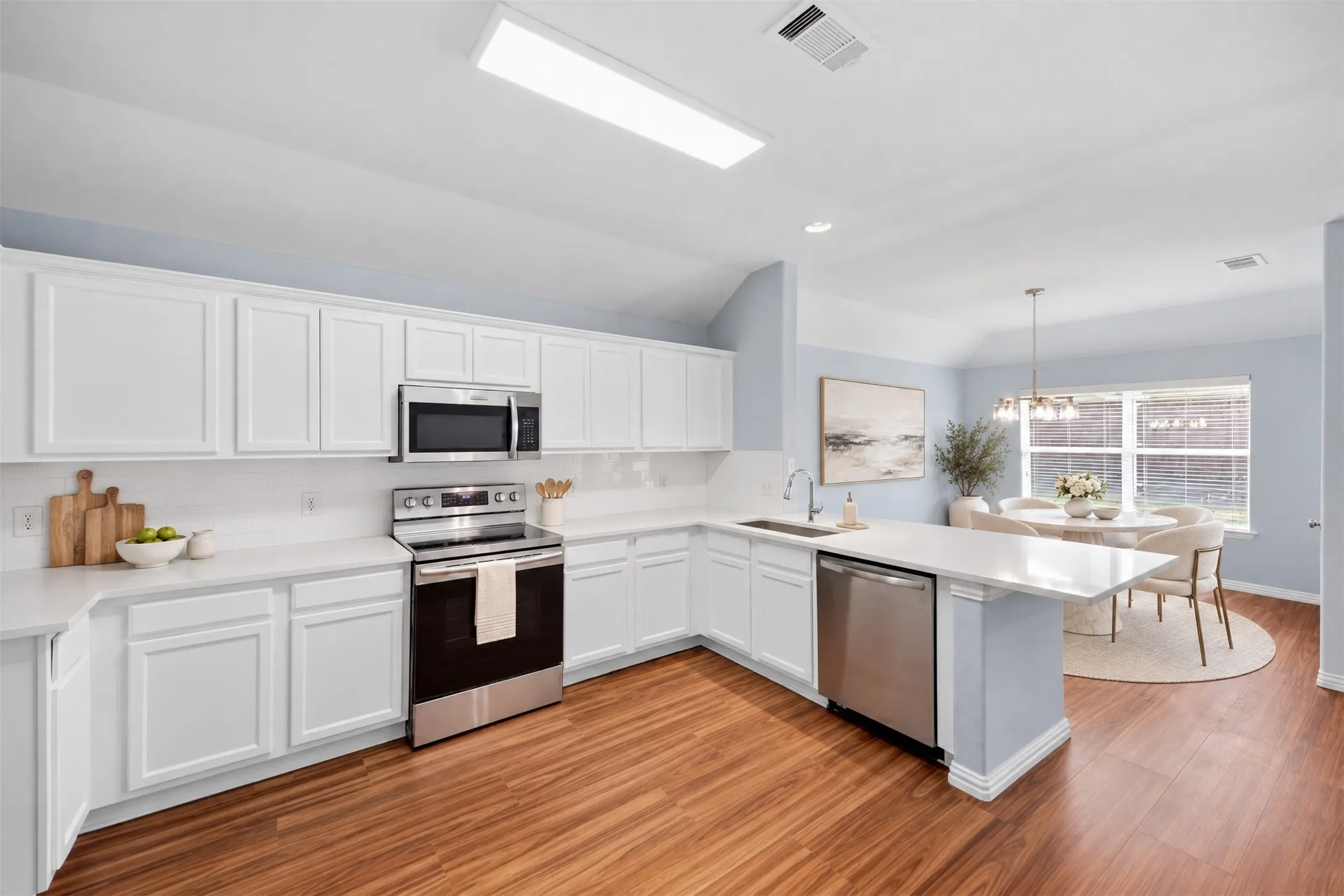 The kitchen shines with new quartz countertops and upgraded stainless steel appliances, opening to a welcoming breakfast area where everyday meals and conversations feel right at home. Virtual staged