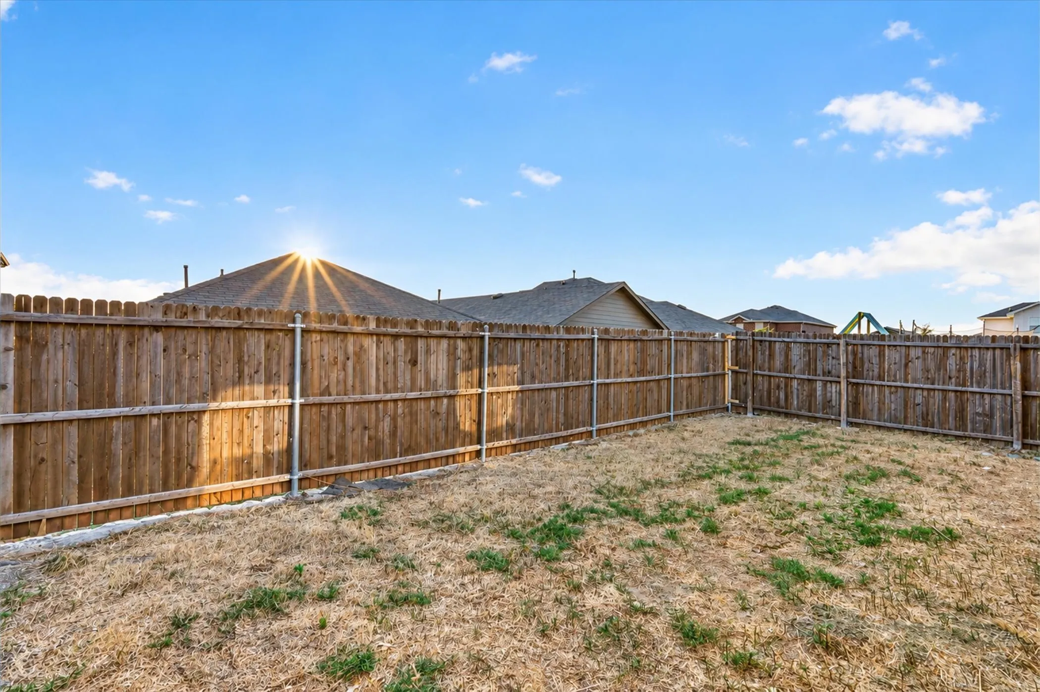 Fenced backyard featuring wood panel fencing with metal posts