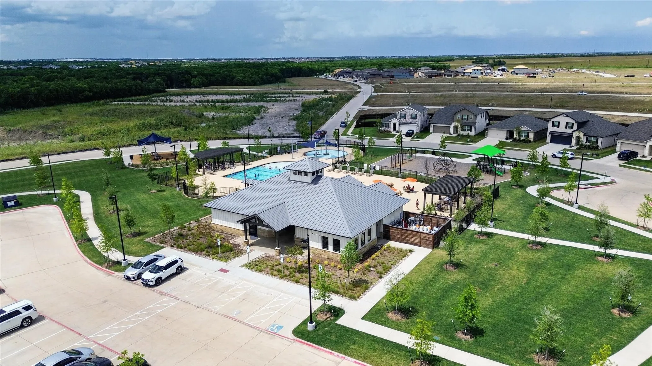 Community amenity center featuring a gabled metal roof and an outdoor patio with a pergola