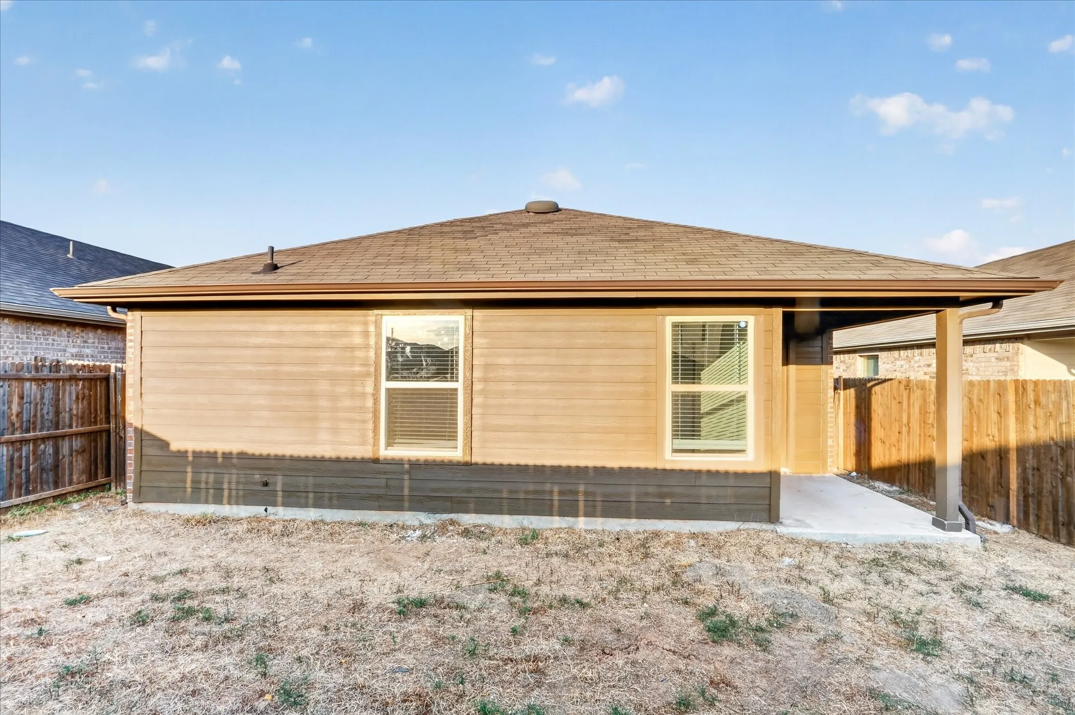 Rear exterior with covered patio, wood-finish siding, and a shingle roof