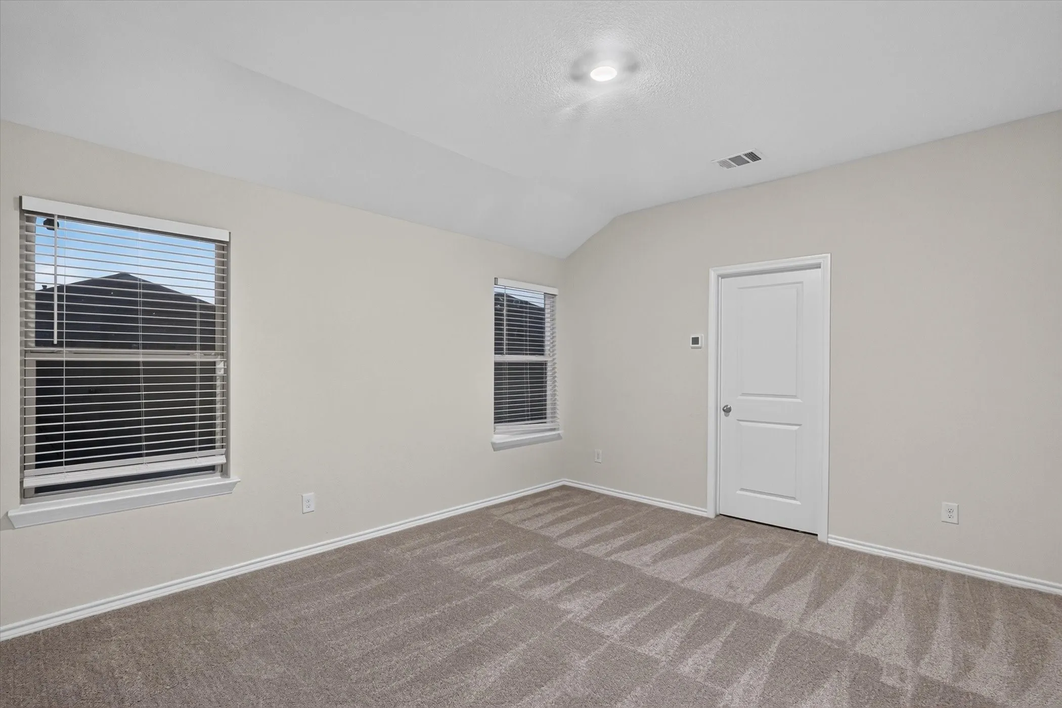 Vaulted ceiling room with two windows, ceiling-mounted light fixture, and carpet flooring
