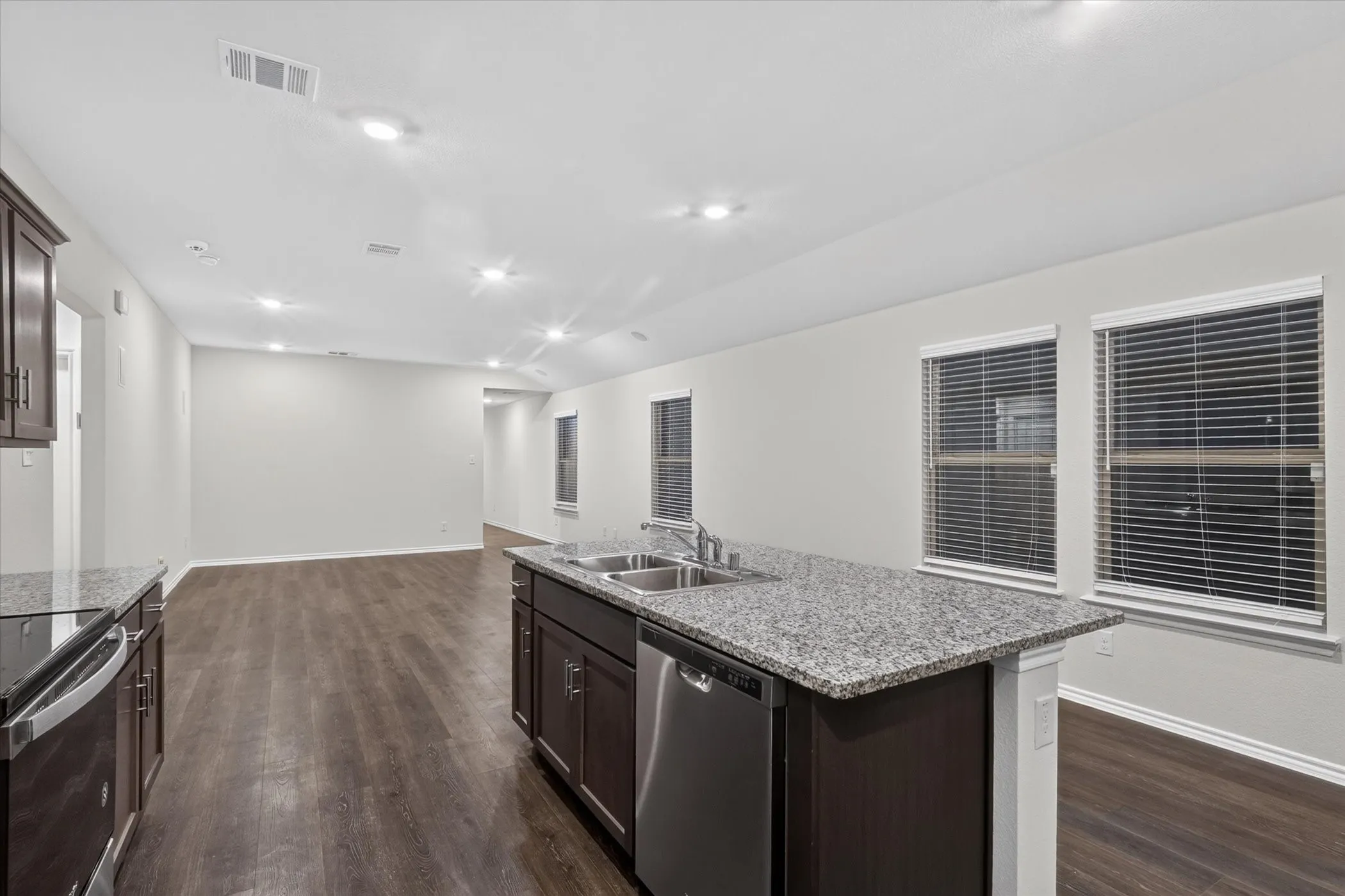 Open-concept living space with wood-finish flooring, recessed lighting, and ample natural light through multiple windows