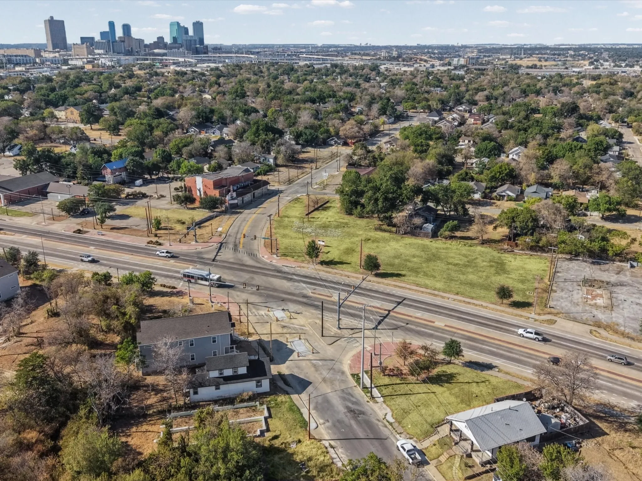 Overhead perspective featuring a structured road network, surrounding residential structures, and a distant city skyline
