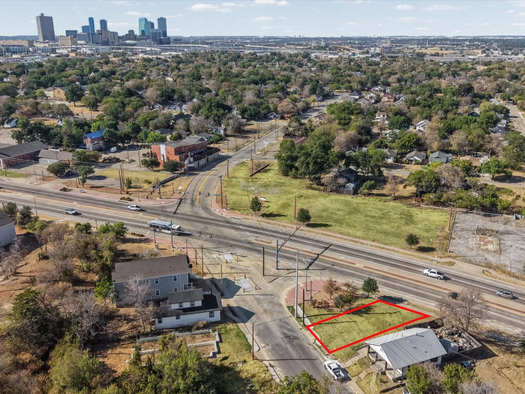 Urban landscape featuring a distant city skyline, mature trees, and a clear sky