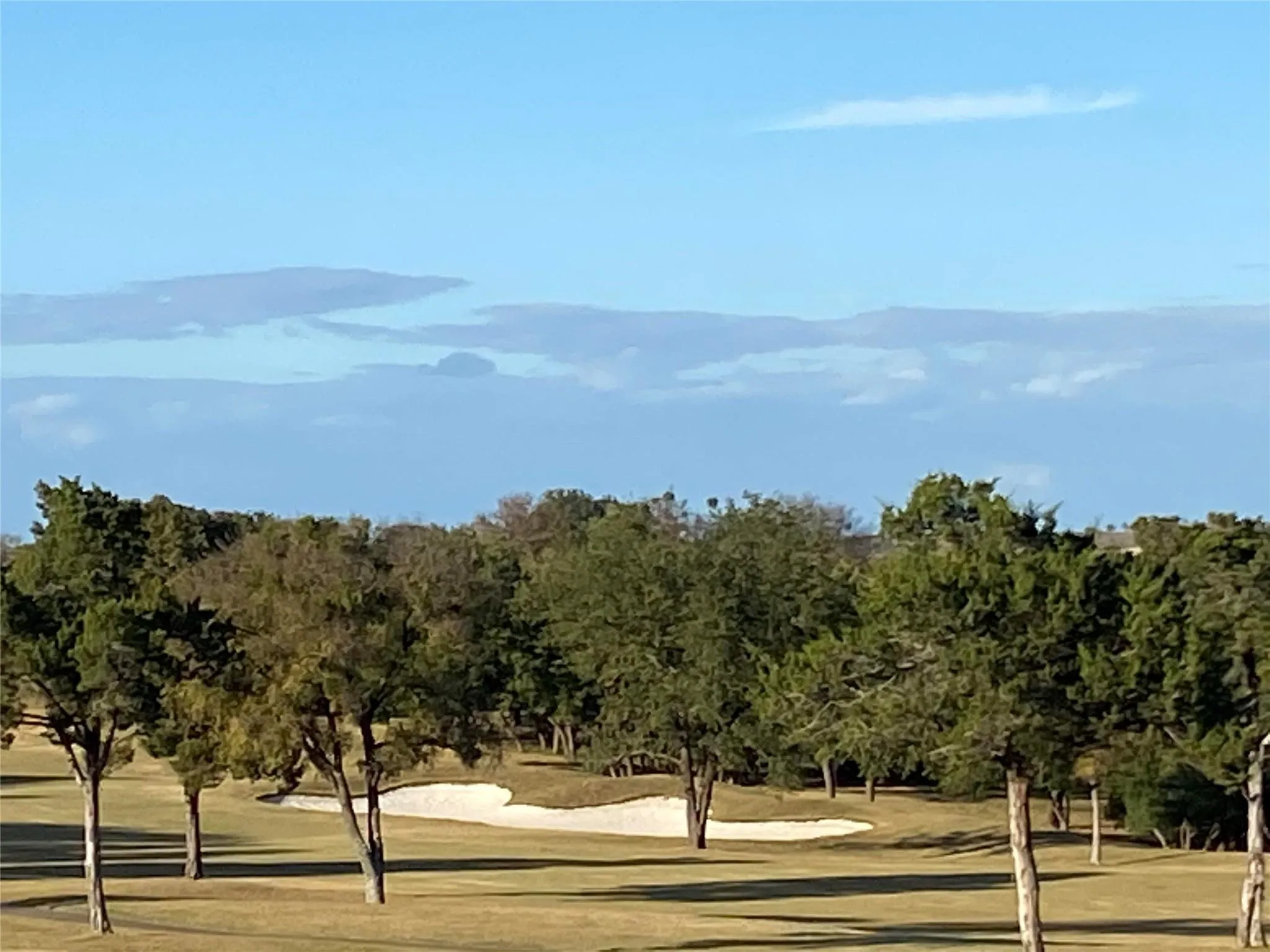 Golf course frontage with mature trees and a sand trap