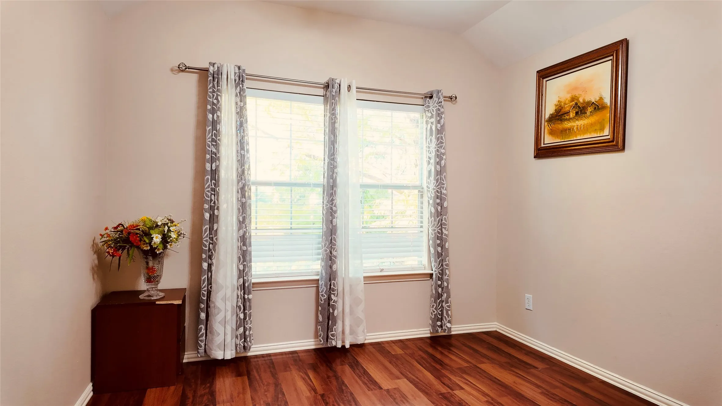 Wood-finish flooring throughout, vaulted ceiling, and dual windows with blinds