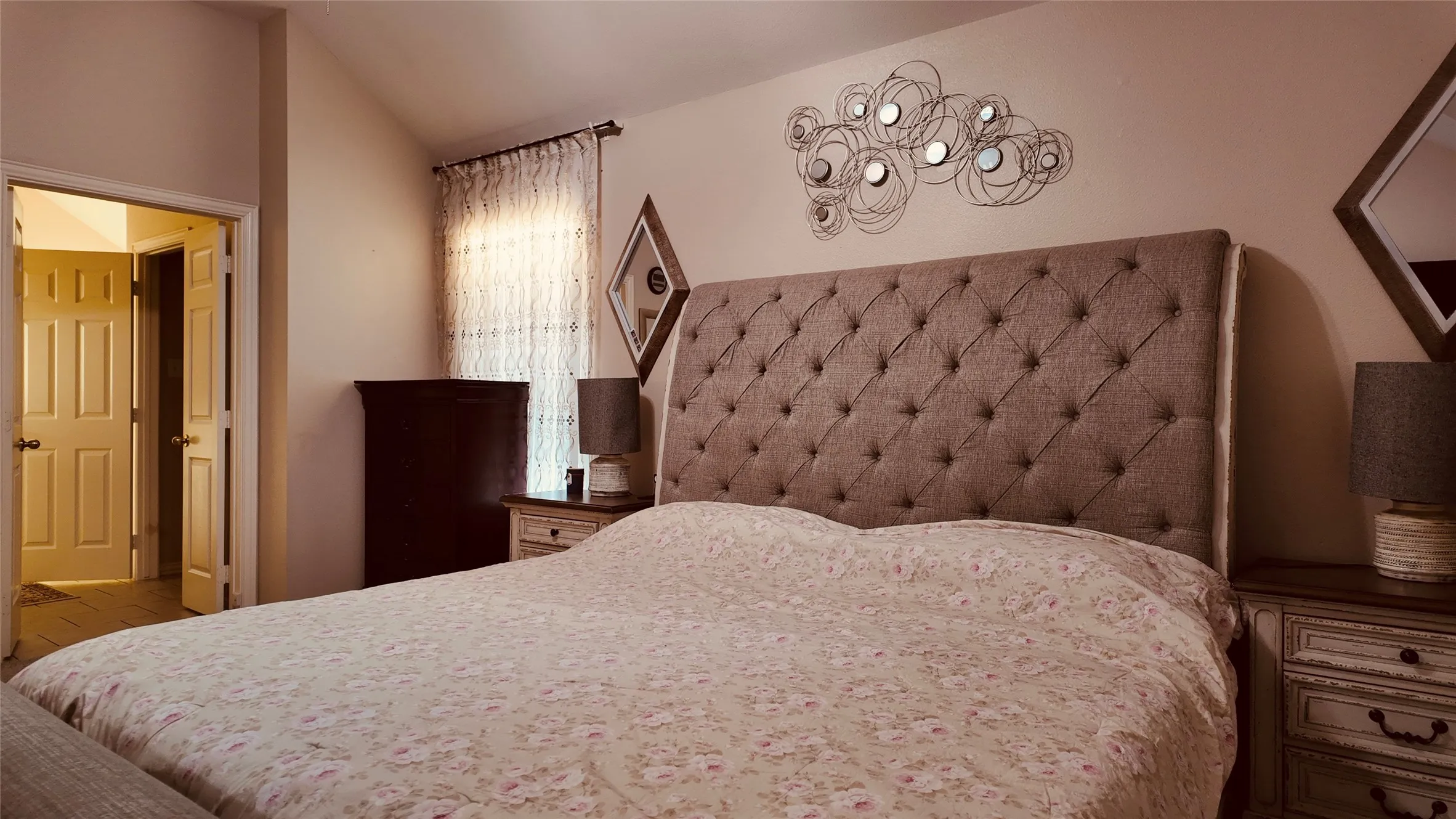 Upholstered button-tufted headboard with dual entryways and window with sheer curtains