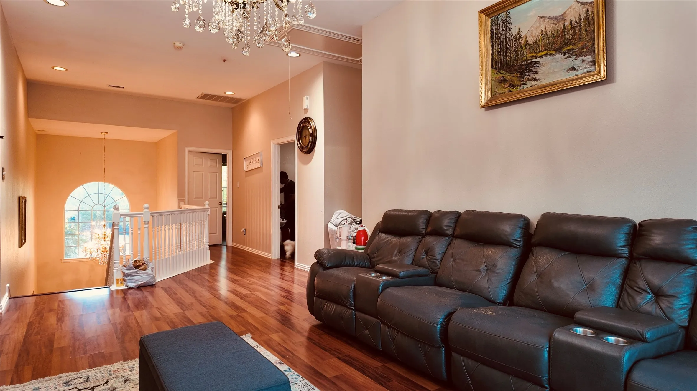 Hardwood-finish flooring, recessed lighting, chandelier, and a white staircase with an arched window