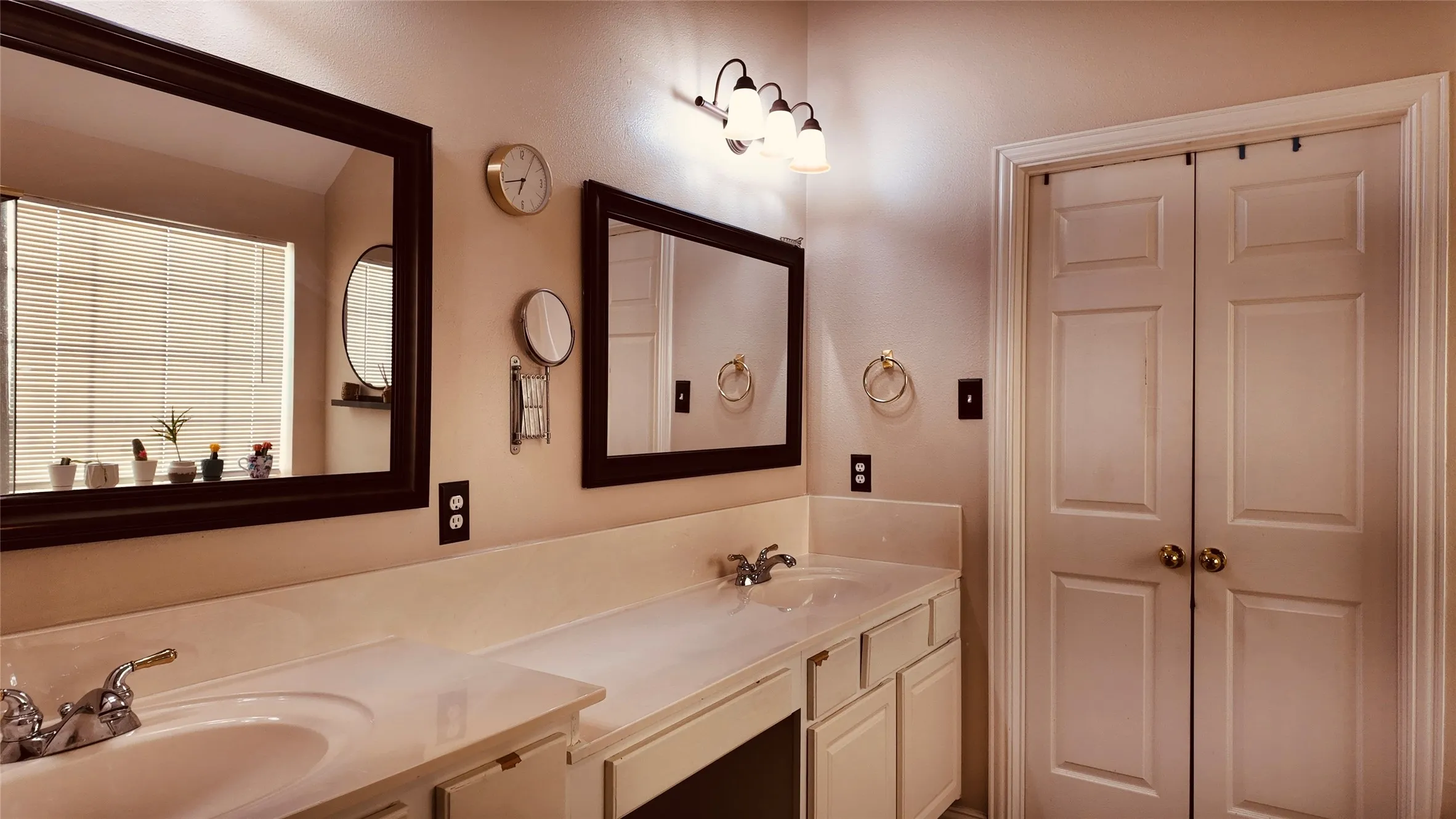 Dual vanity with integrated sinks, framed mirrors, and a multi-bulb light fixture