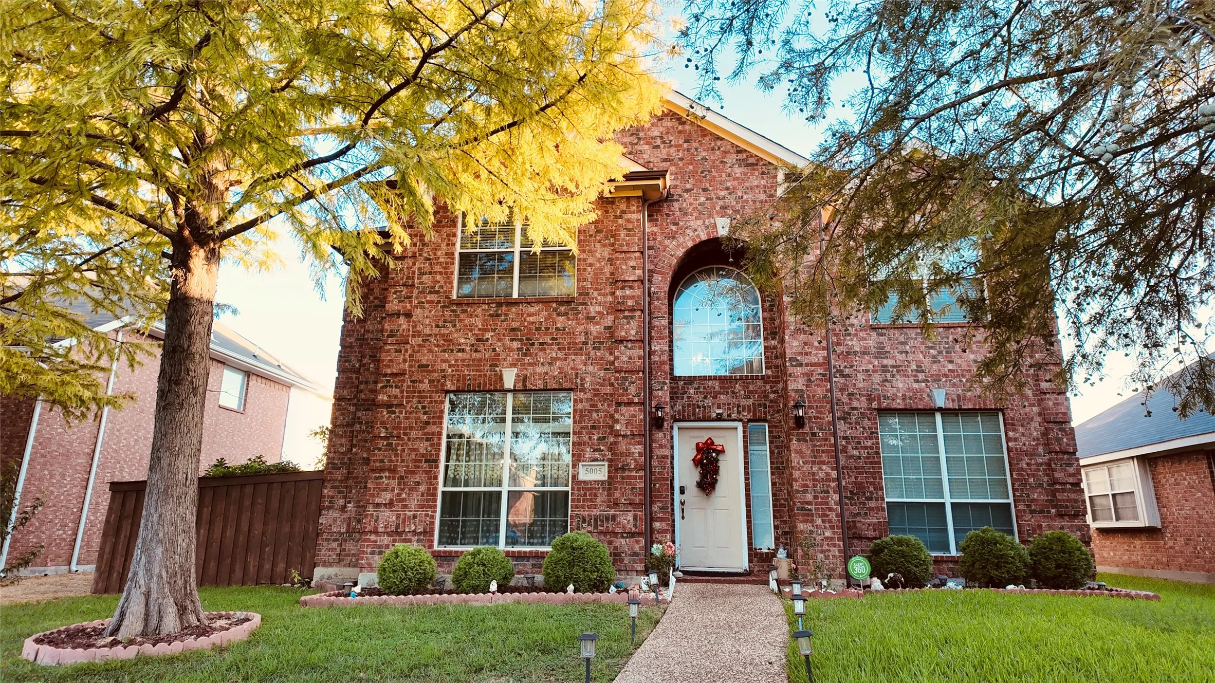 Brick exterior with an arched window, white entry door, and ground-level landscaping
